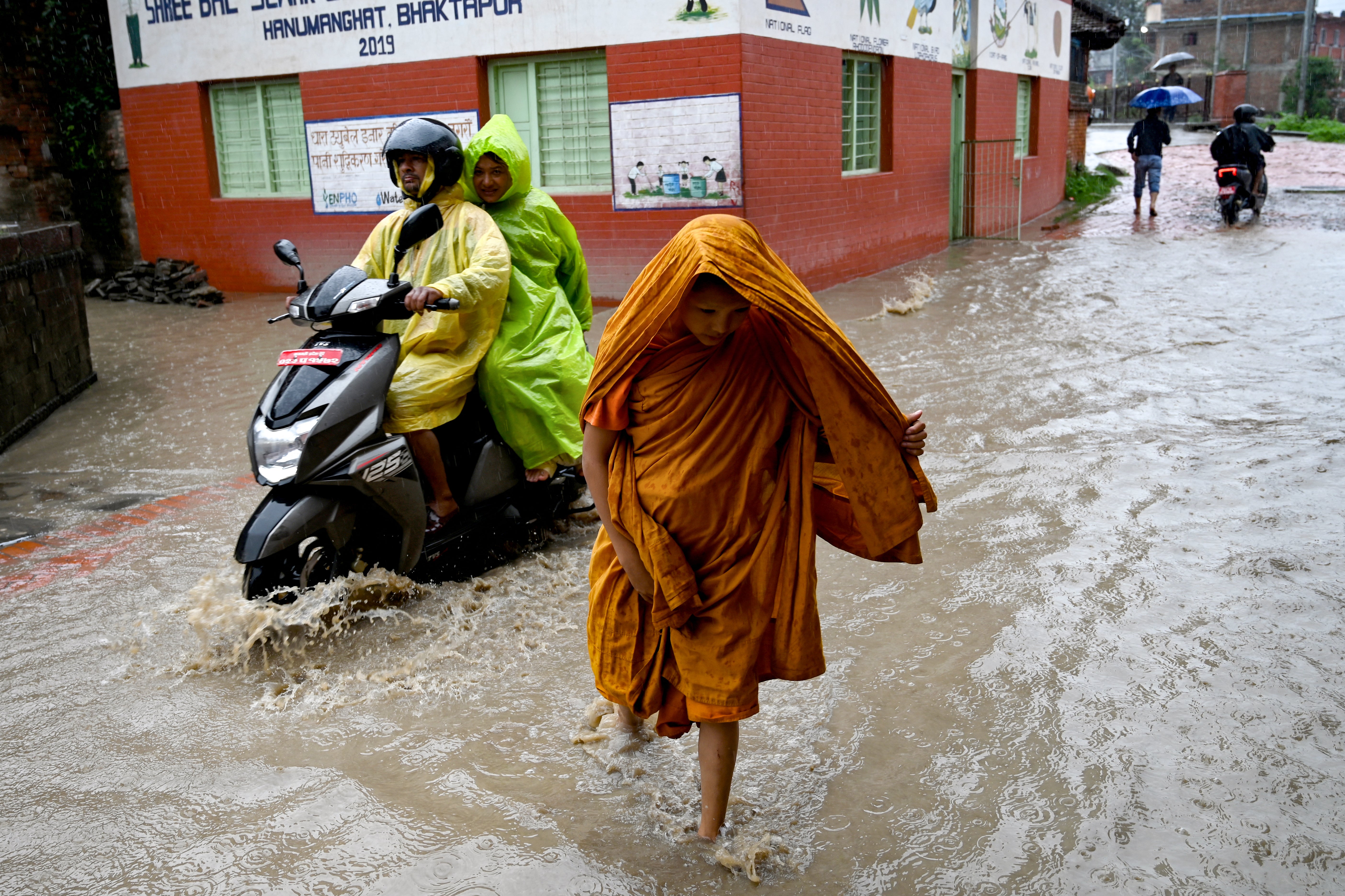 <p>File. People wade through floodwaters after the Hanumante river overflowed on the outskirts of Kathmandu, Nepal, in July</p>