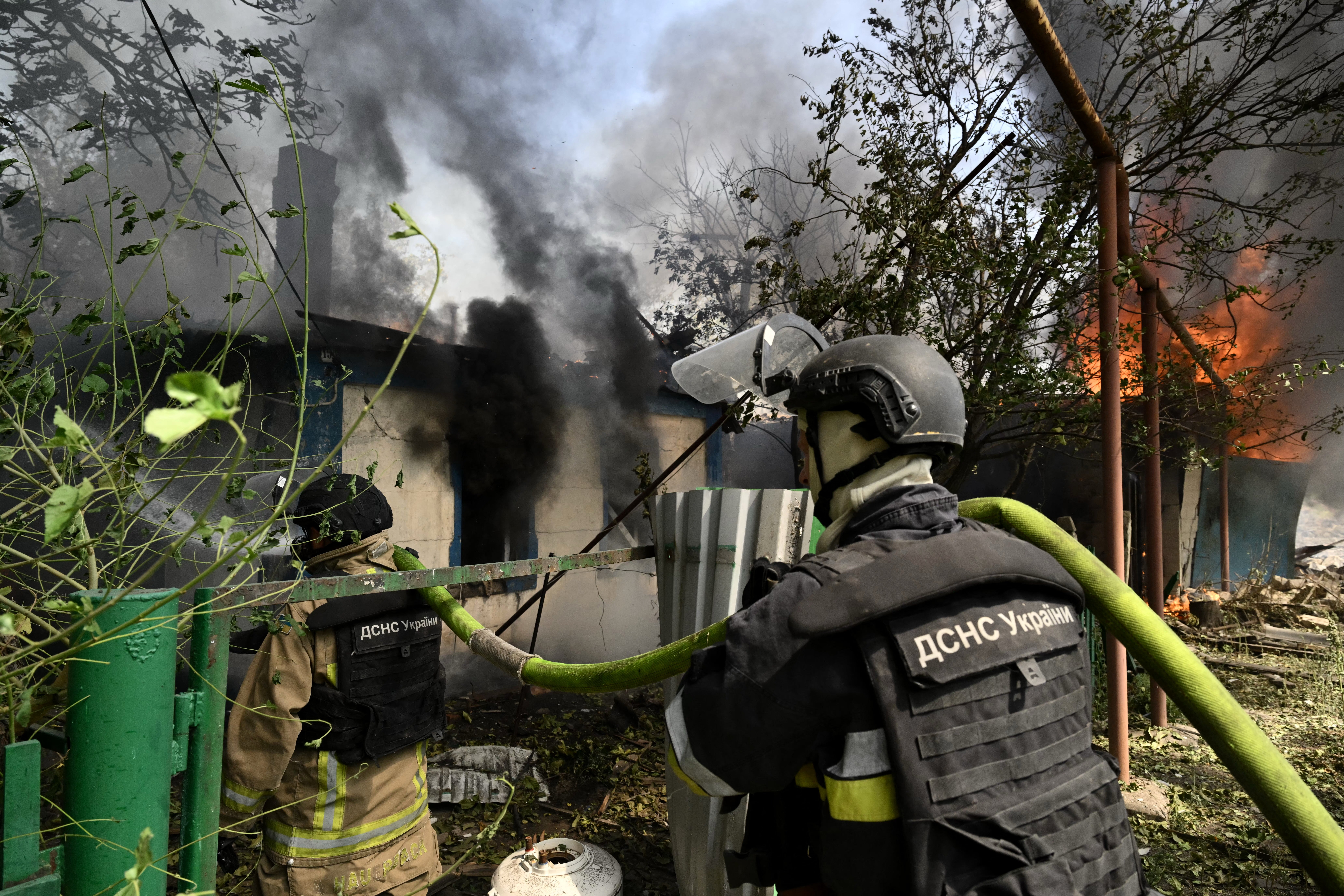 Ukrainian firefighters work to extinguish a fire in a private house that broke out a day after a missile attack in Myrnograd, Donetsk region