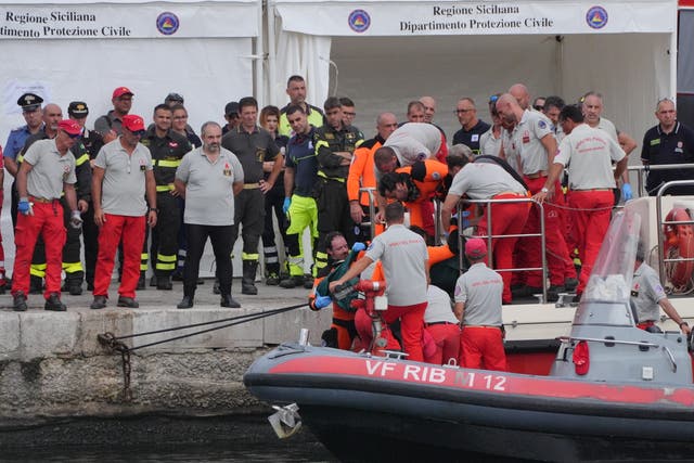 <p>A body bag is brought ashore at the harbour in Porticello </p>