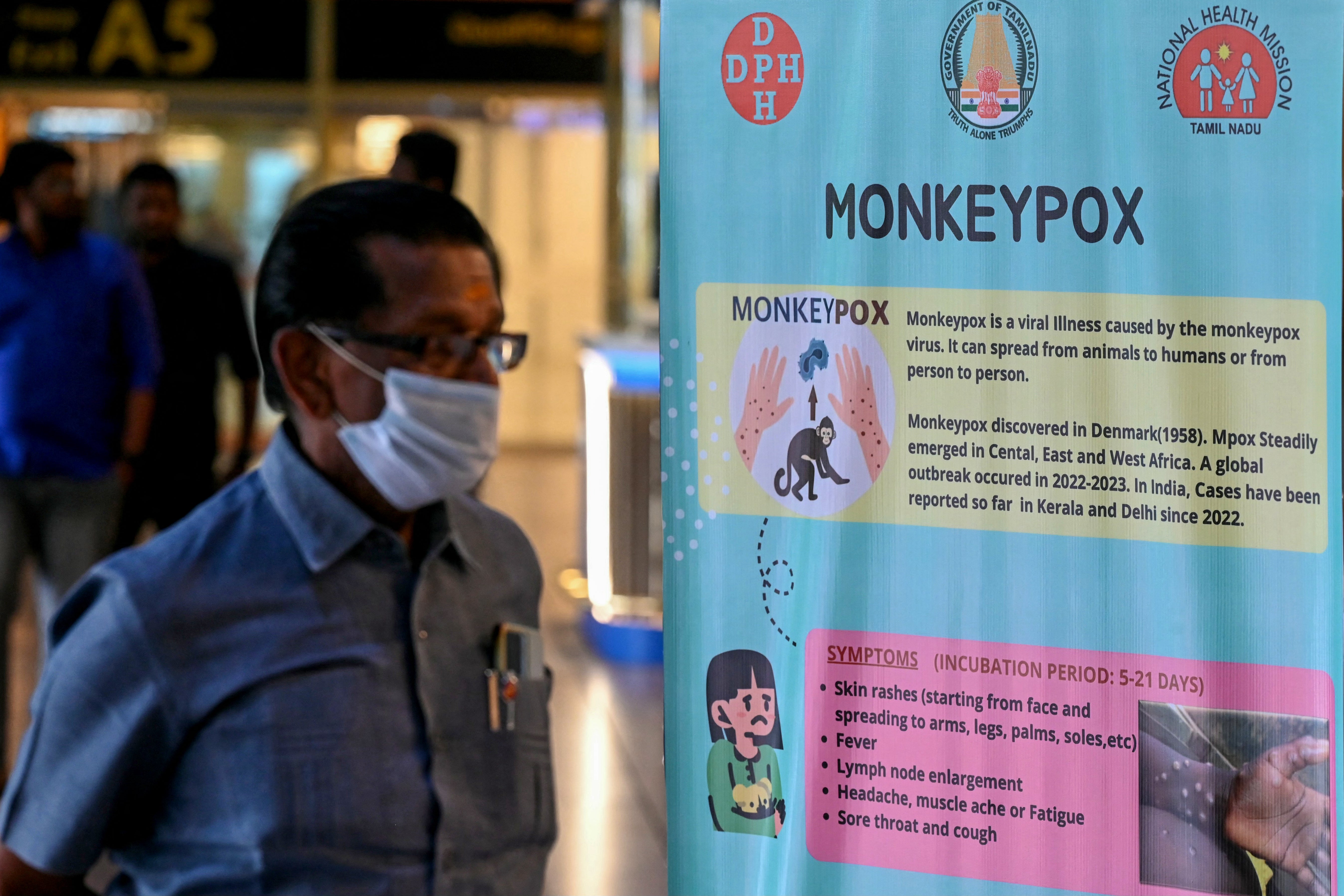 Passengers walk past the mpox awareness banner at Anna International Airport terminal in Chennai