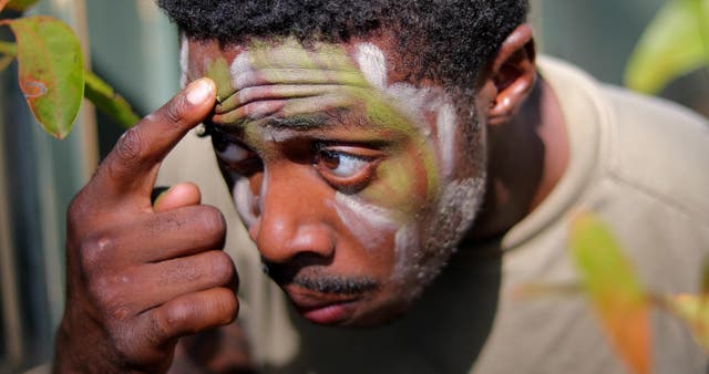<p>U.S. Army Pfc. Dewayne Johnson applies face paint during a training exercise</p>