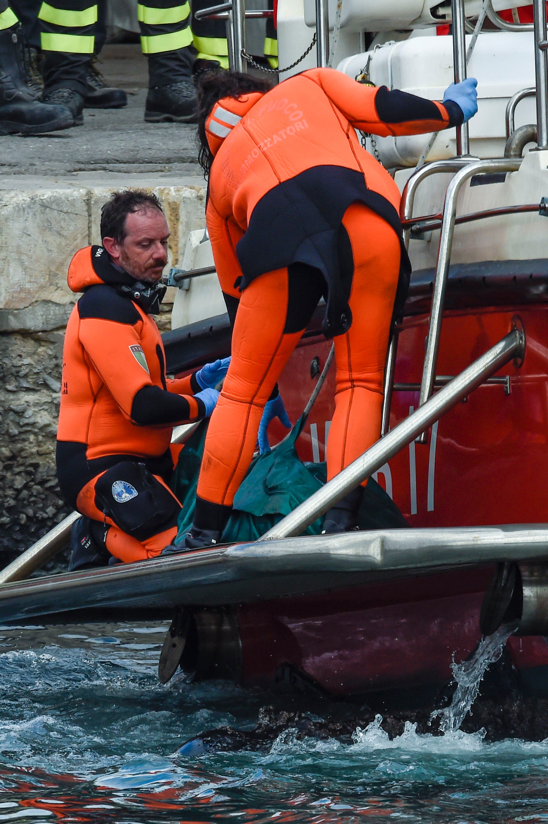 Italian firefighter divers bring ashore in a green bag the body of one of the victims on Wednesday following the sinking of the Bayesian