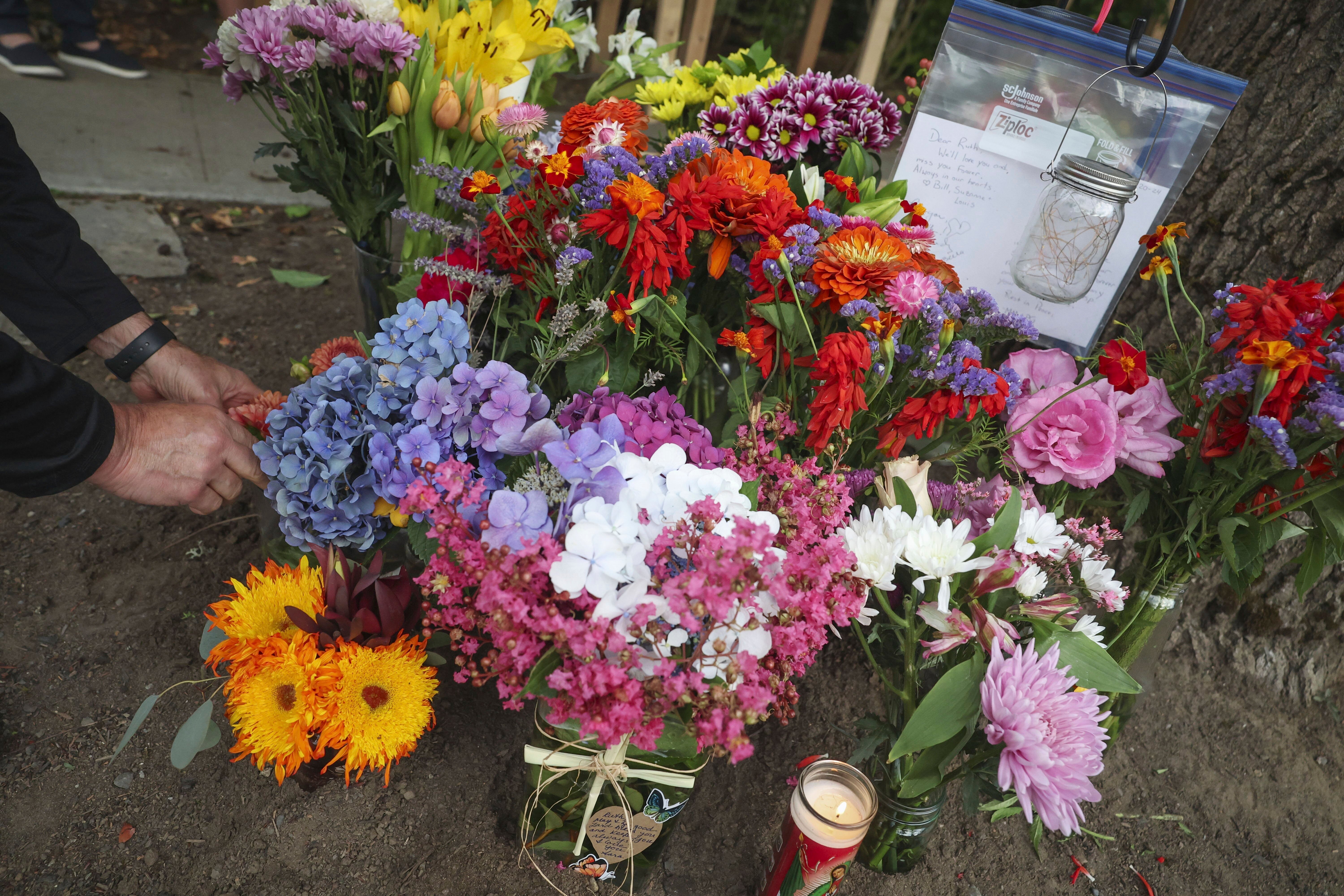 A visitor places flowers on a memorial for a beloved neighborhood dog walker