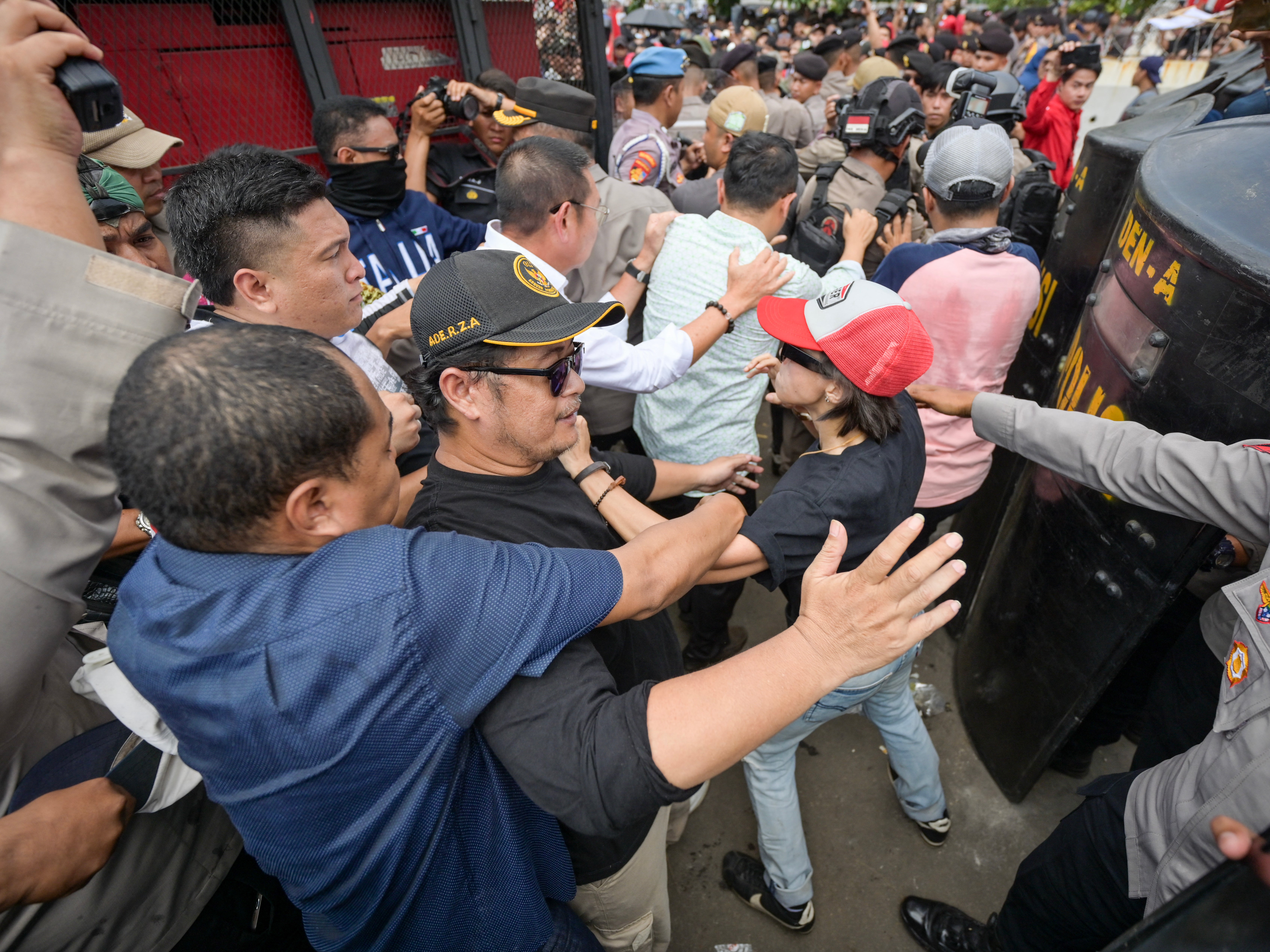 Policemen try to shield parliament members as they attempt to meet with protesters in Jakarta on 22 August 2024