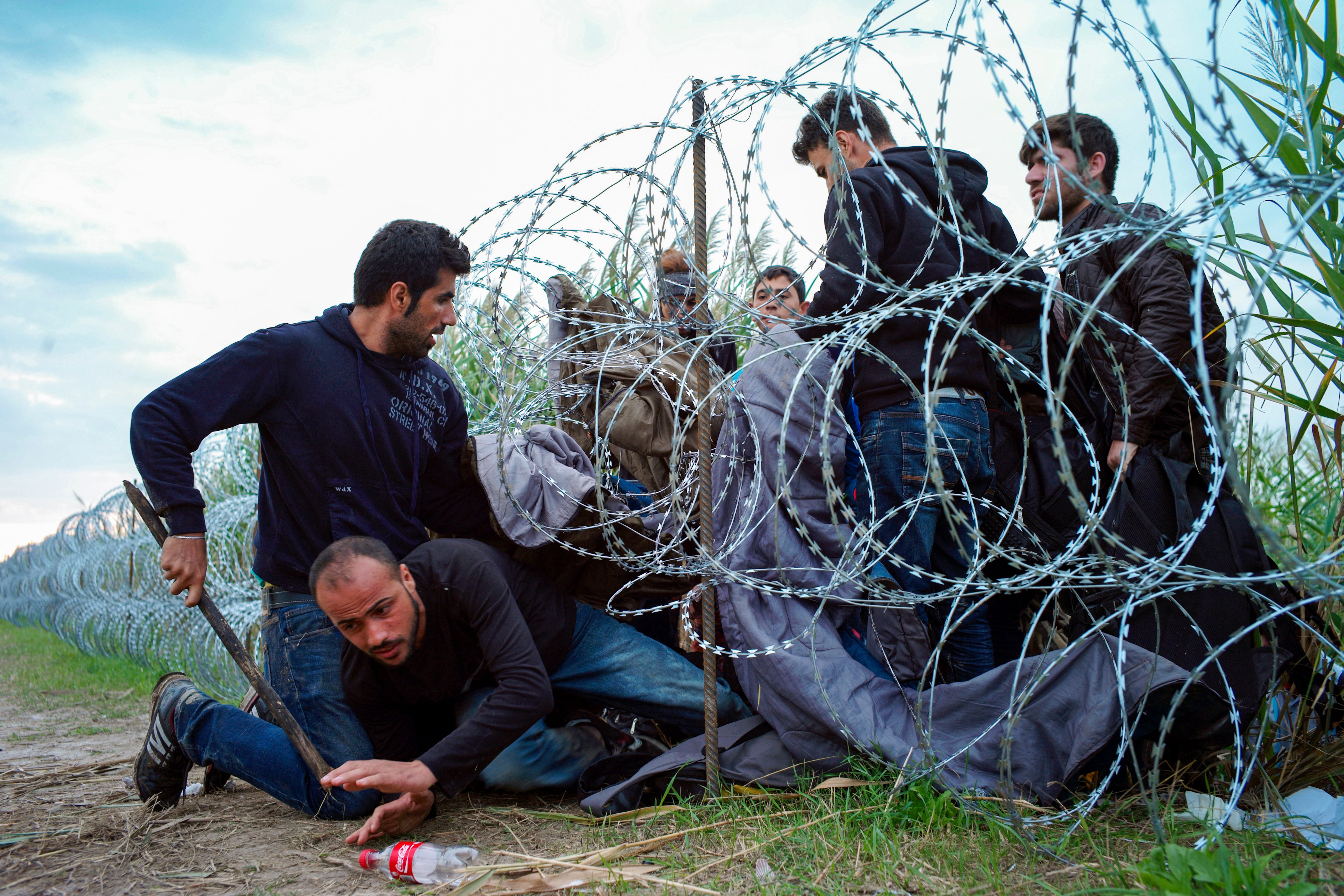 Syrian refugees cross into Hungary underneath the border fence on the Hungarian - Serbian border