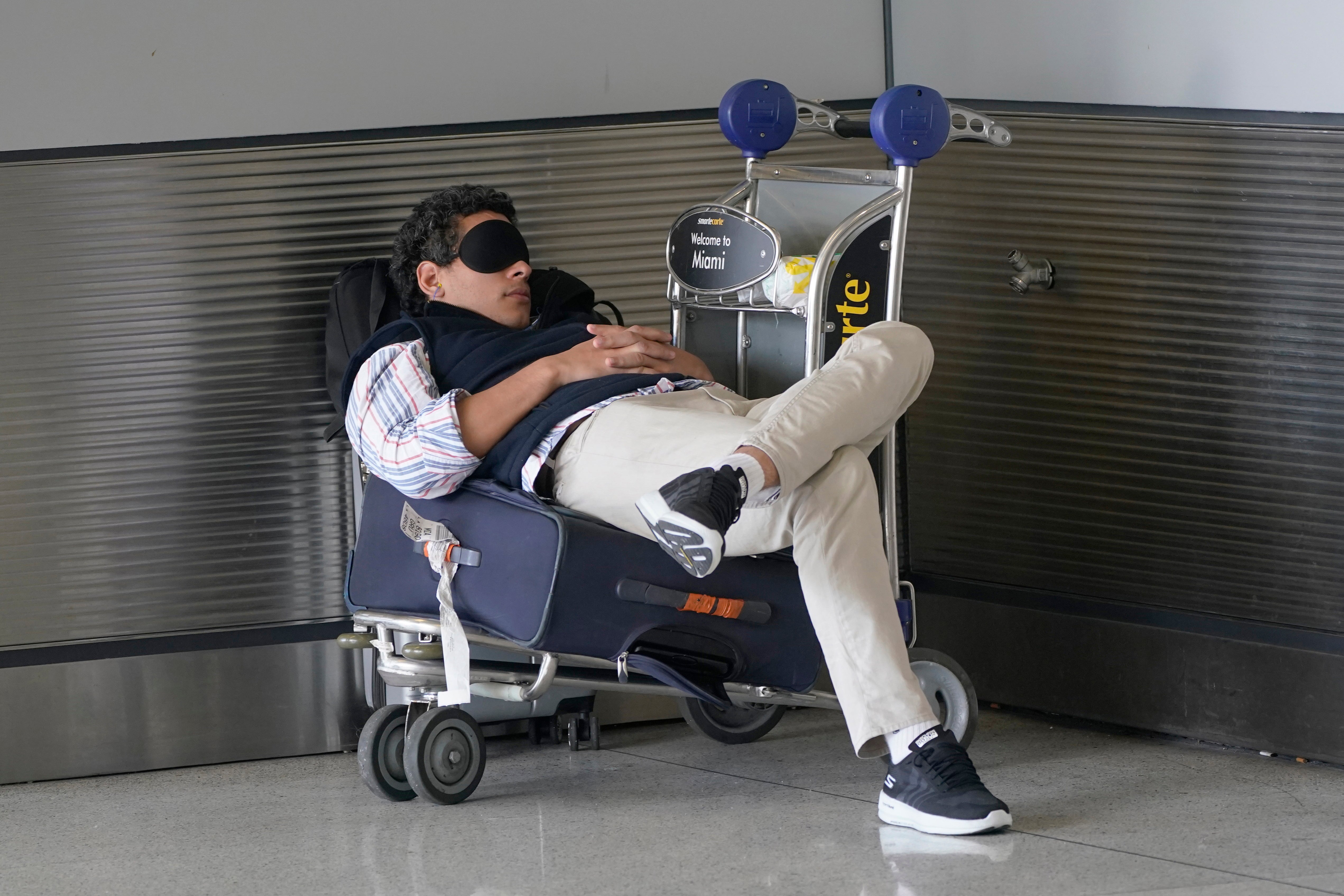 A traveler takes a nap as he waits for a ride outside Miami International Airport