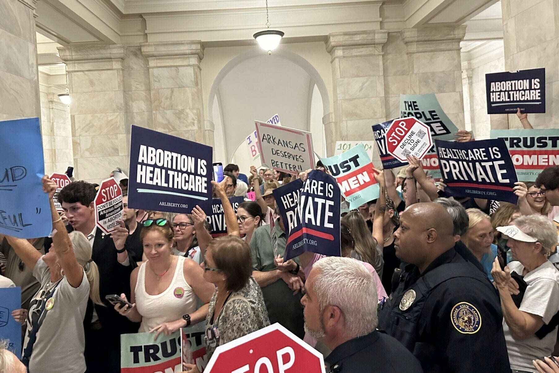 Supporters and opponents of a proposed ballot measure to repeal Arkansas's abortion ban hold signs outside the old Supreme Court chamber at the state Capitol in July.