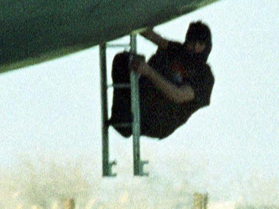 A hijacker with a gun in his hand climbs down a ladder under the cockpit of an Indian Airlines plane in Kandahar, Afghanistan on December 30, 1999.