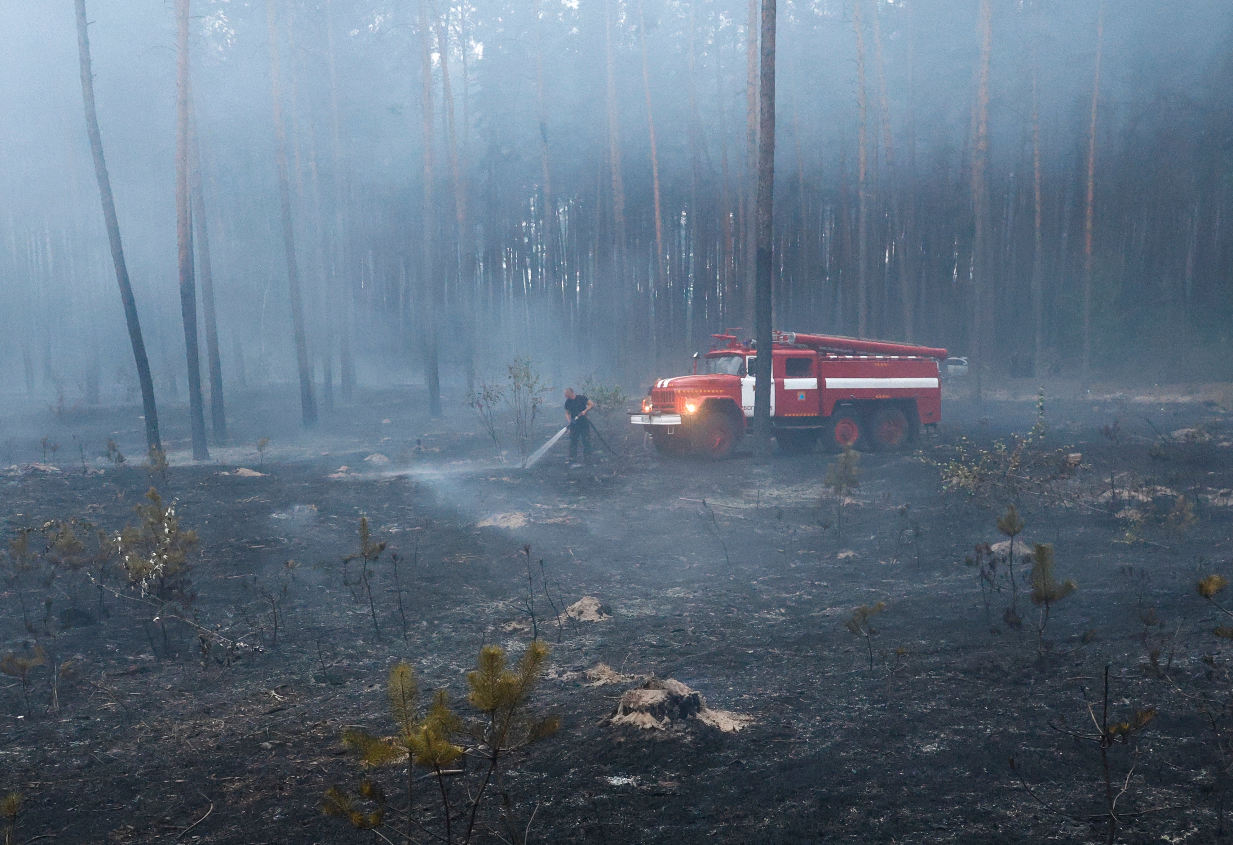 Ukrainian rescuers work to extinguish a fire in a forest after shelling in the city of Bogodukhiv, Kharkiv region, northeastern Ukraine