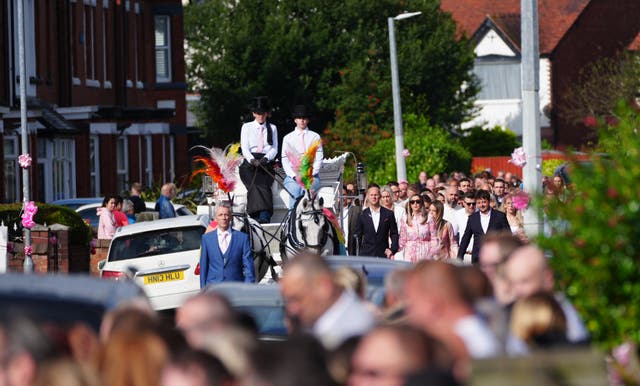 <p>A procession led by two white horses passed by hundreds of people in the streets of Southport</p>