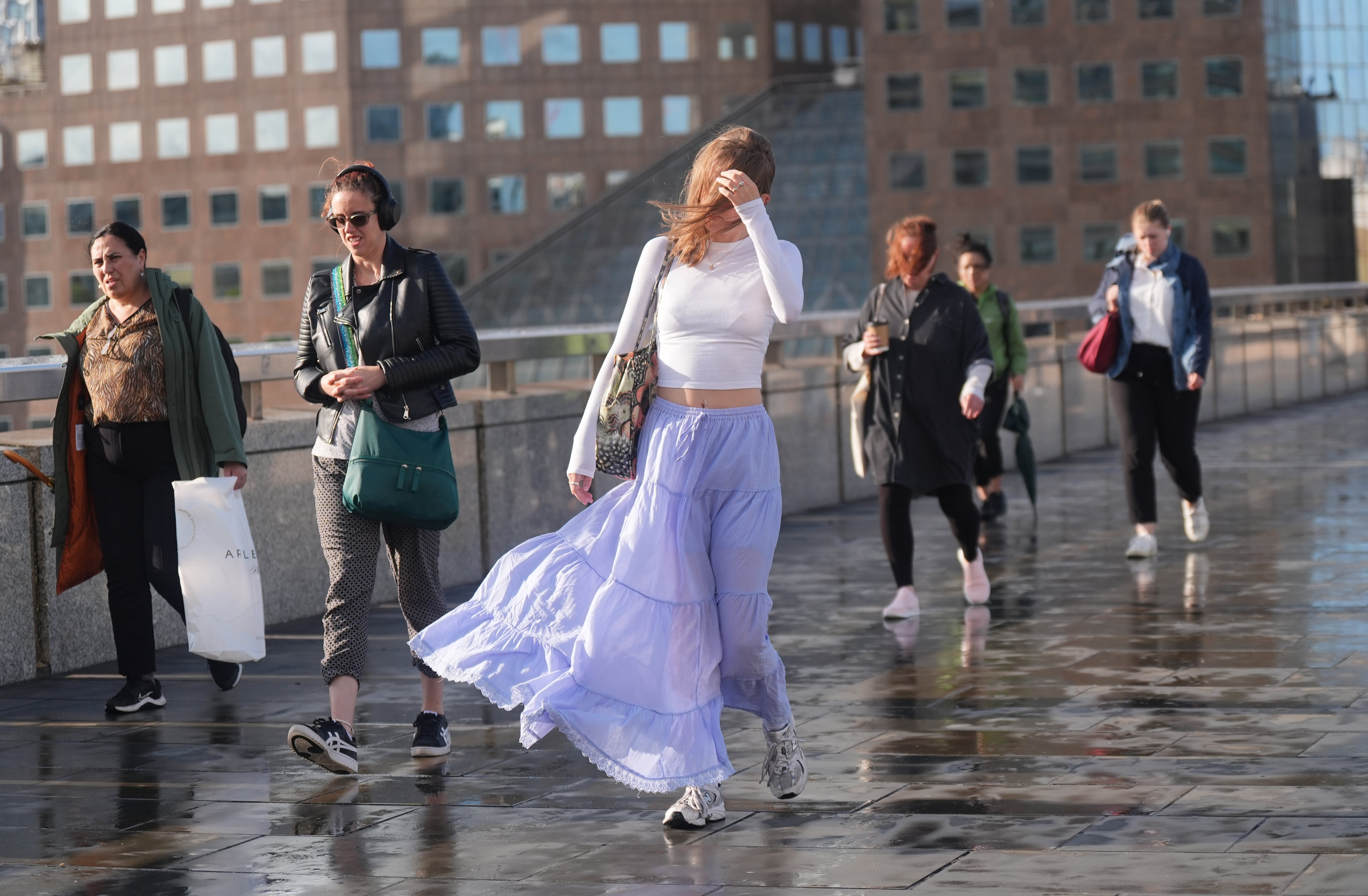 People walk on London Bridge in windy conditions as Storm Lilian hits the UK