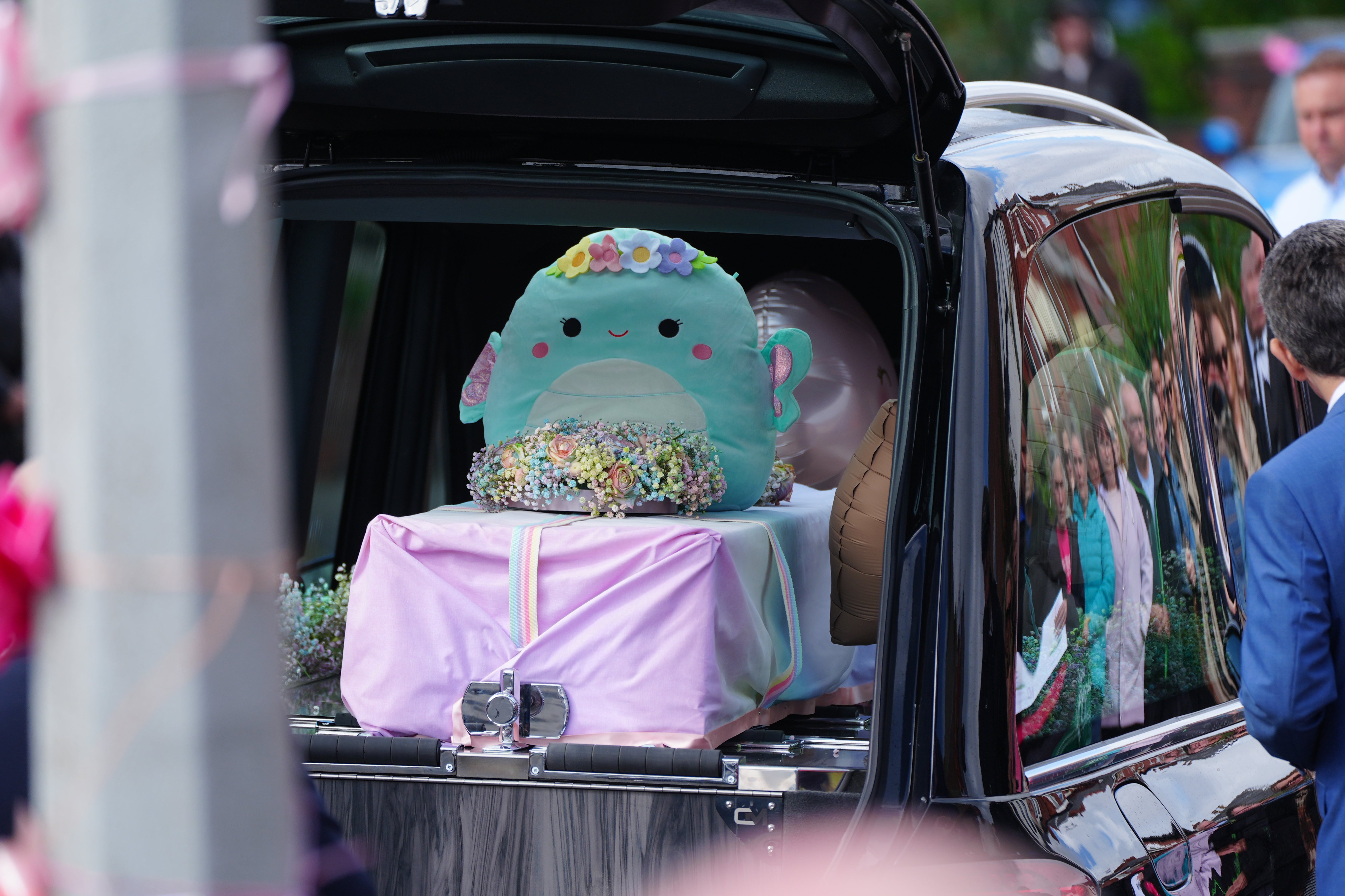 The coffin, decorated with a big blue toy, was carried away following the service