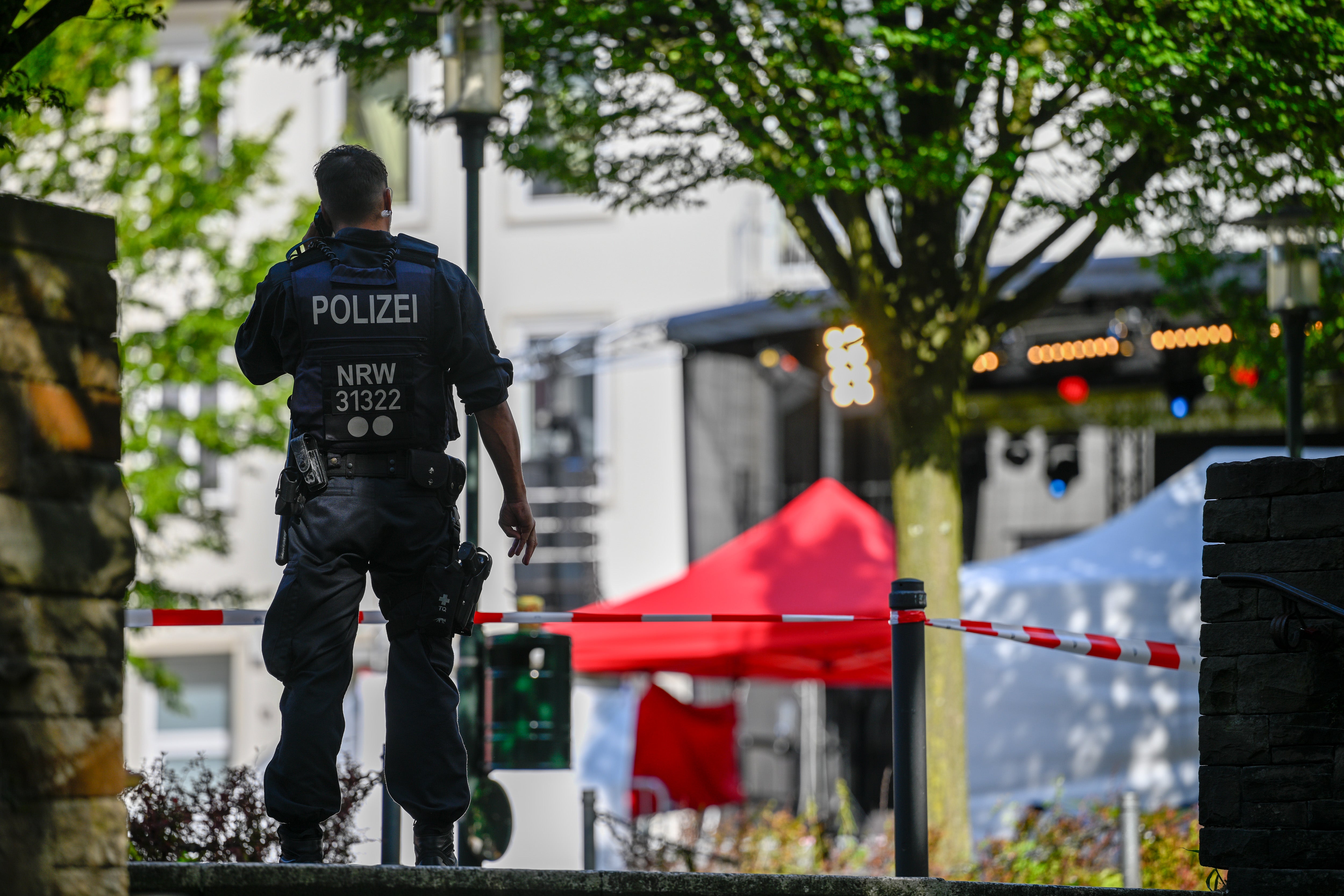 Police investigators stand at the site of yesterday's deadly stabbings that left three dead and eight injured