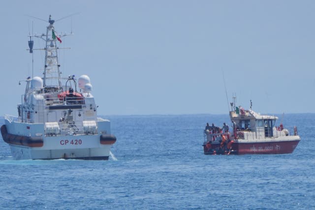 Members of a rescue team place a body bag onto the lower half of the deck of the fire service dive team boat on the fifth day of the search and recovery operation, after the luxury yacht Bayesian sank in a storm on Monday while moored around half a mile off the coast of Porticello, Sicily (Jonathan Brady/PA)