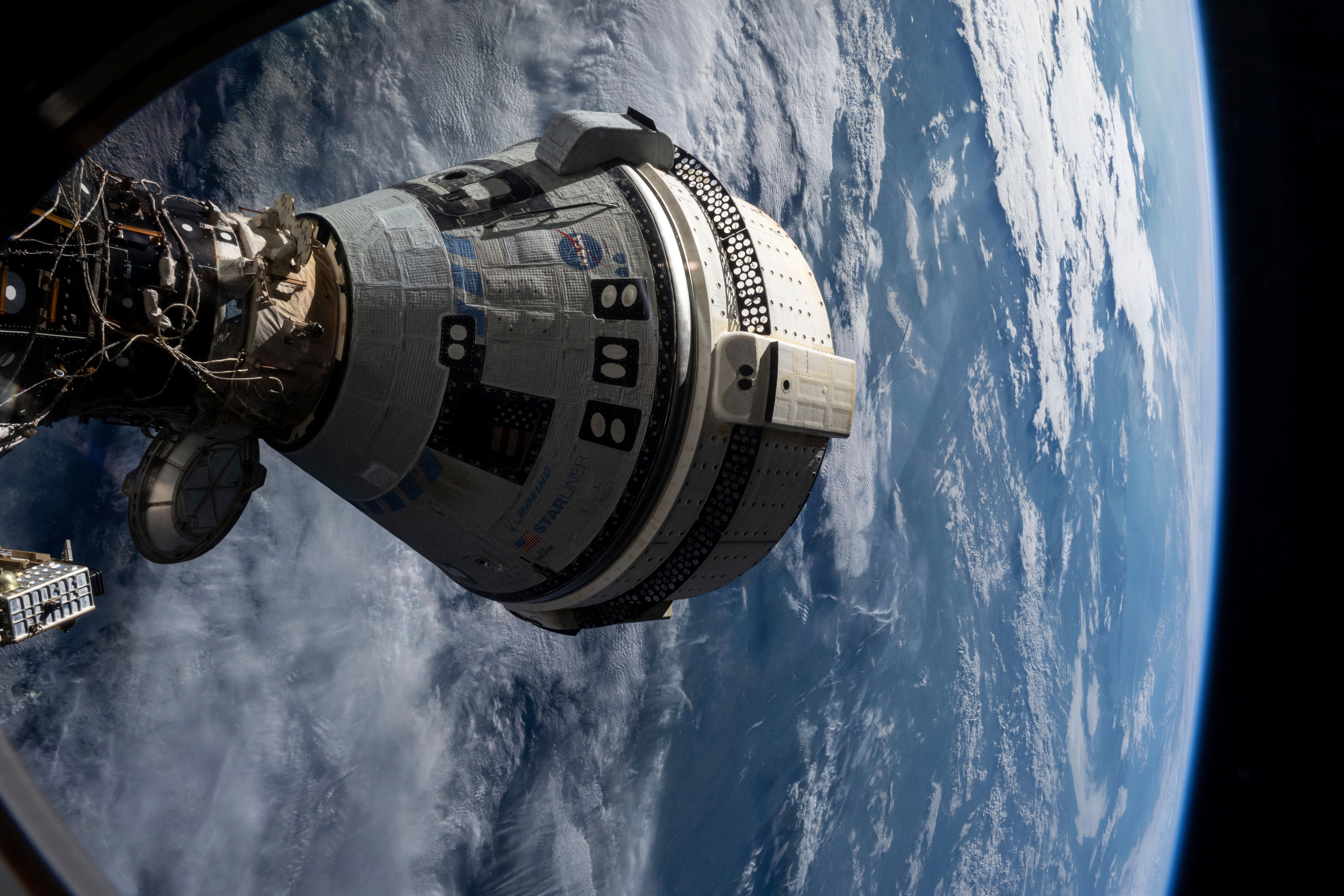 In this photo provided by NASA, Boeing's Starliner spacecraft is docked to the Harmony module of the International Space Station on July 3, 2024, seen from a window on the SpaceX Dragon Endeavour spacecraft docked to an adjacent port