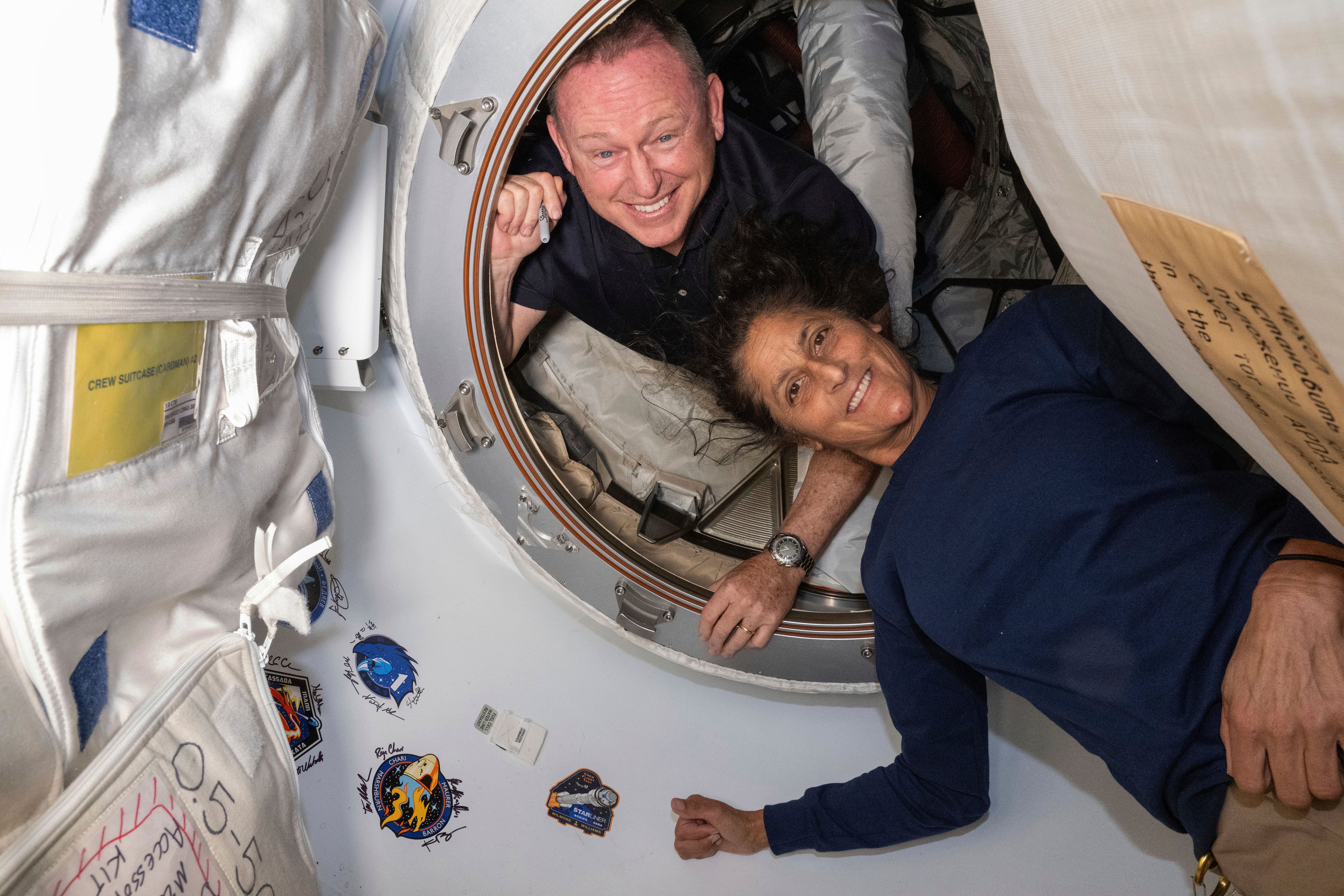 Boeing Crew Flight Test astronauts Butch Wilmore, left, and Suni Williams pose for a portrait in the vestibule between the forward port of the International Space Station's Harmony module and Boeing's Starliner spacecraft on June 13.