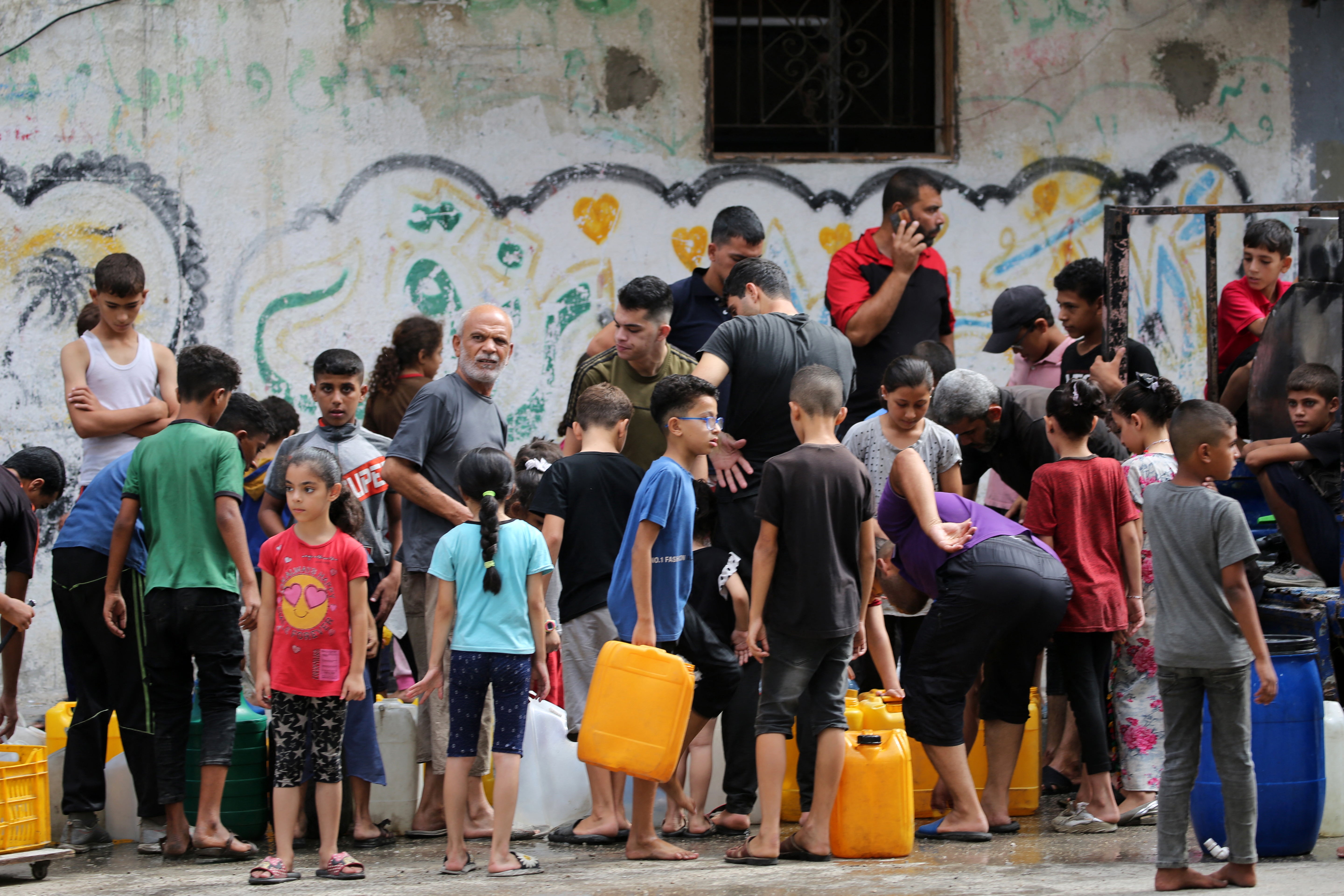 Palestinian children queue at a water distribution point in the Bureij refugee camp in central Gaza Strip