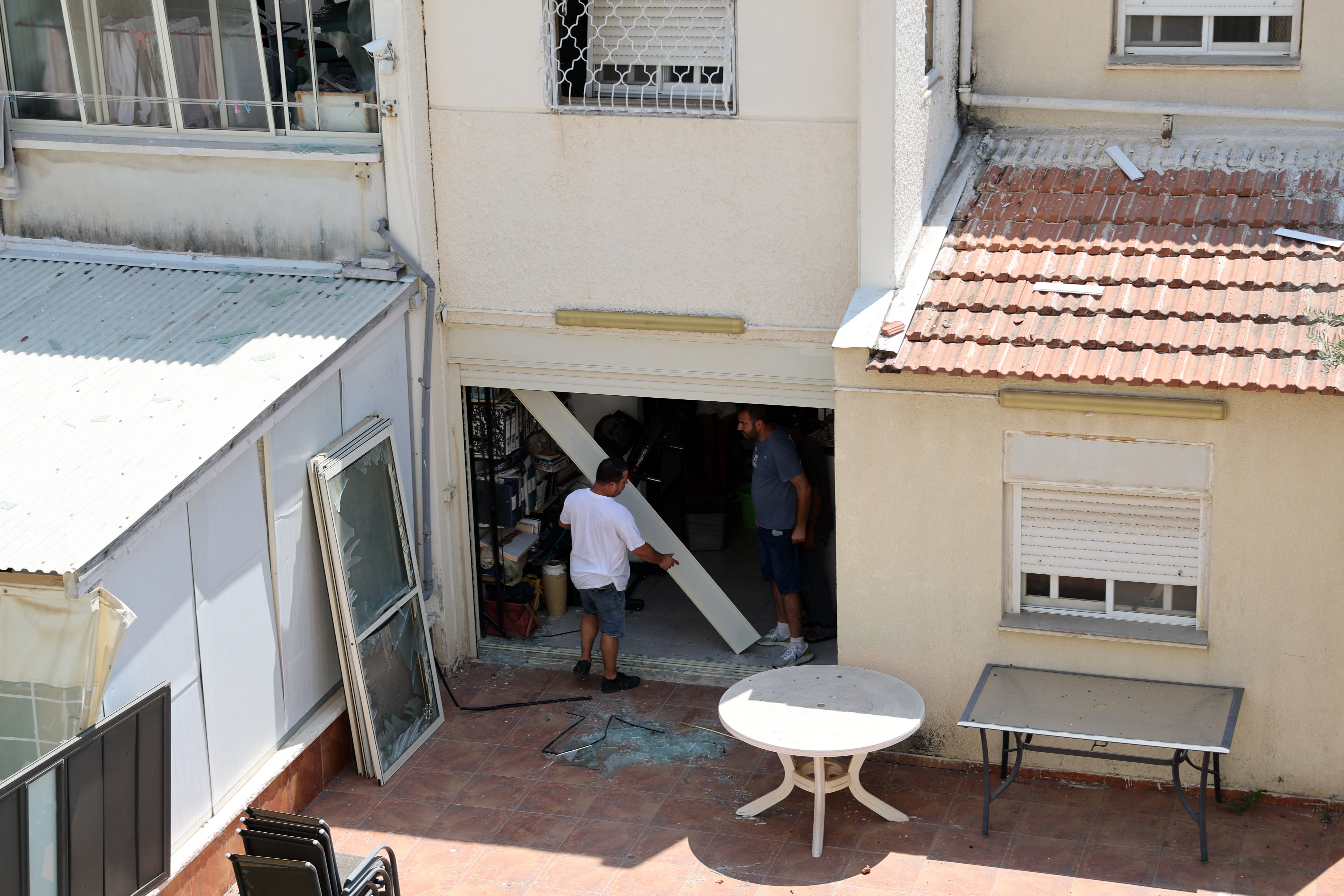 Residents check the damage caused by a rocket fired from Lebanon in the Israeli coastal town of Acre