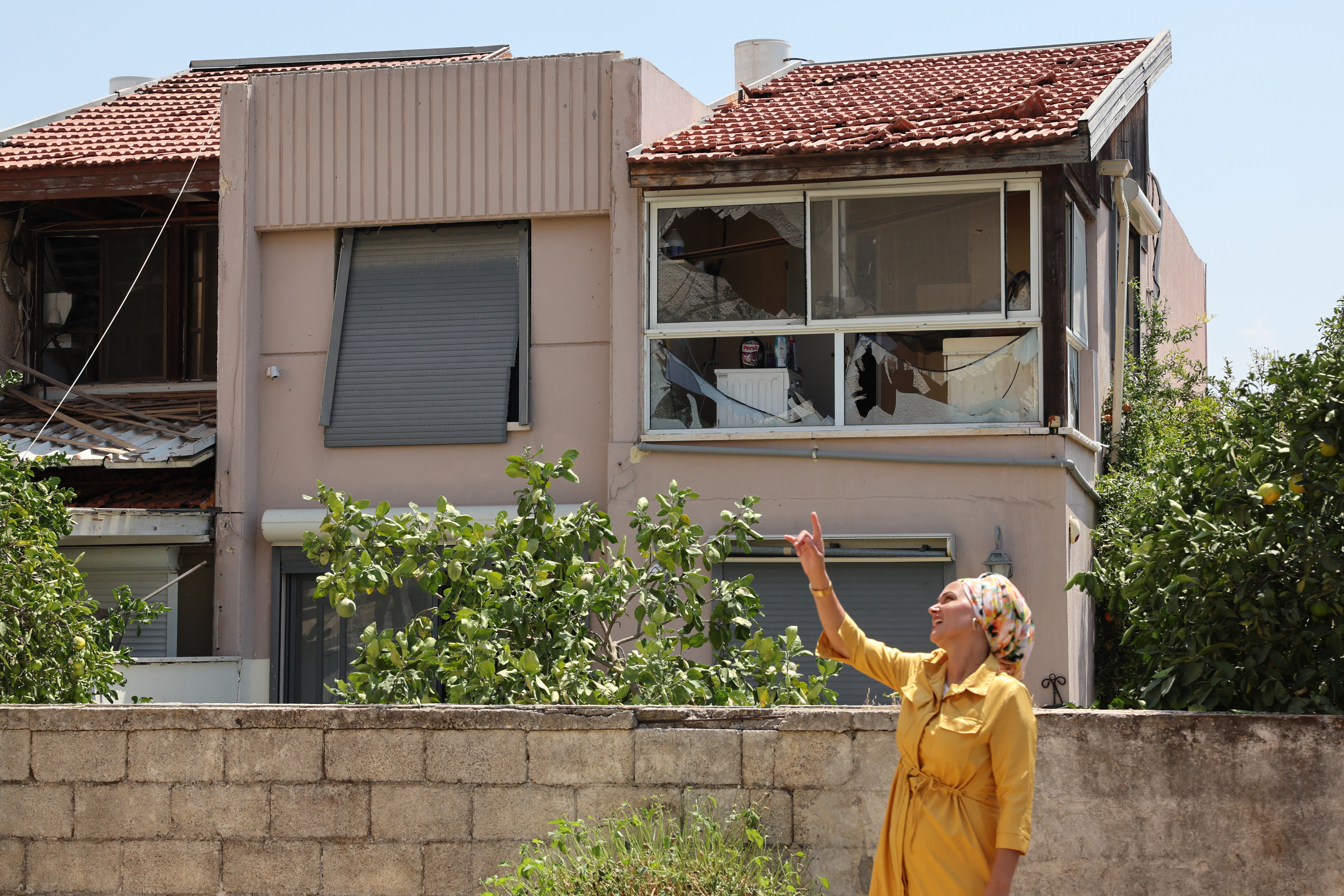 A resident stands next to a house damaged by a rocket fired from Lebanon in the Israeli coastal town of Acre