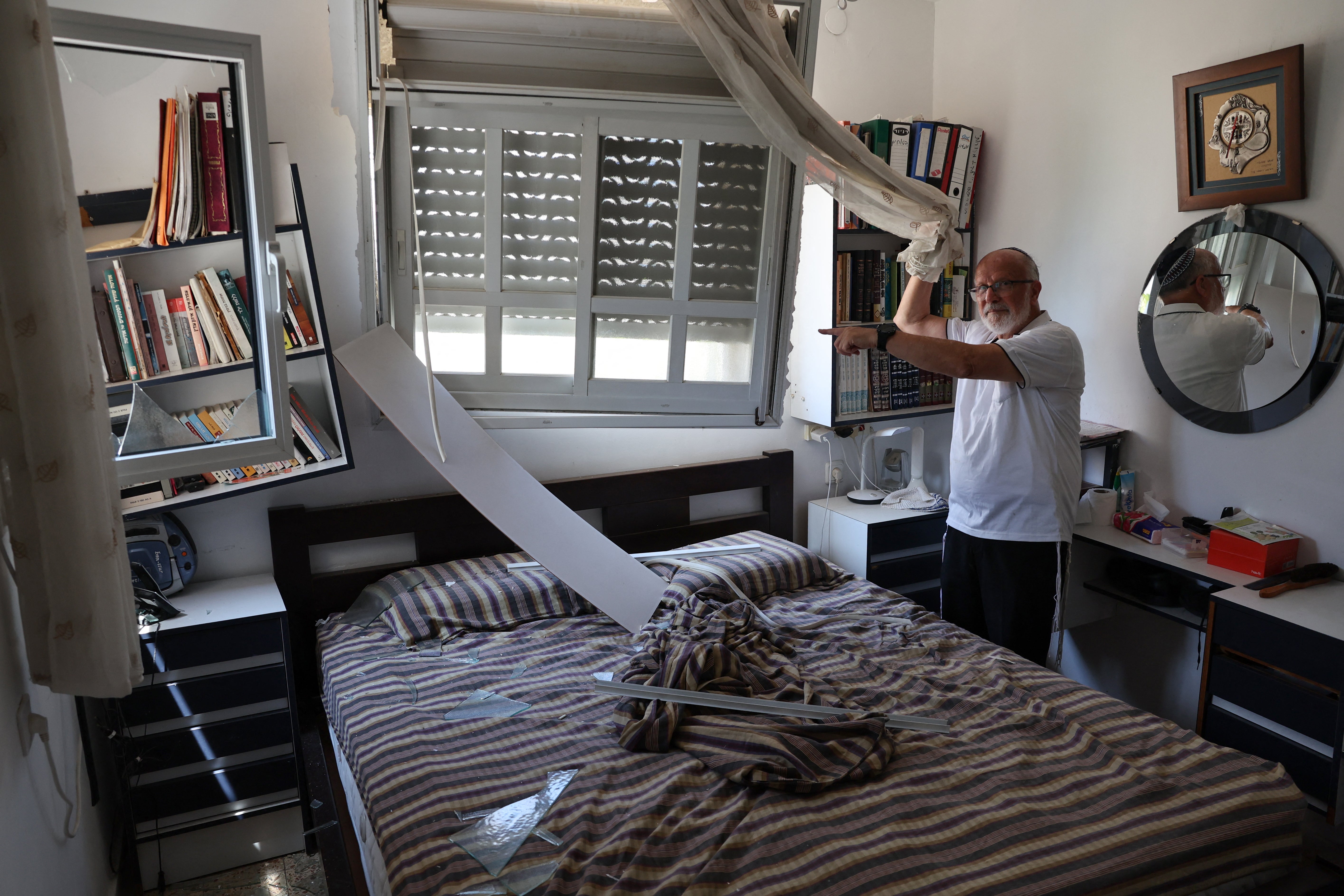 A resident points at the damage inside a house caused by a rocket fired from Lebanon in the Israeli coastal town of Acre