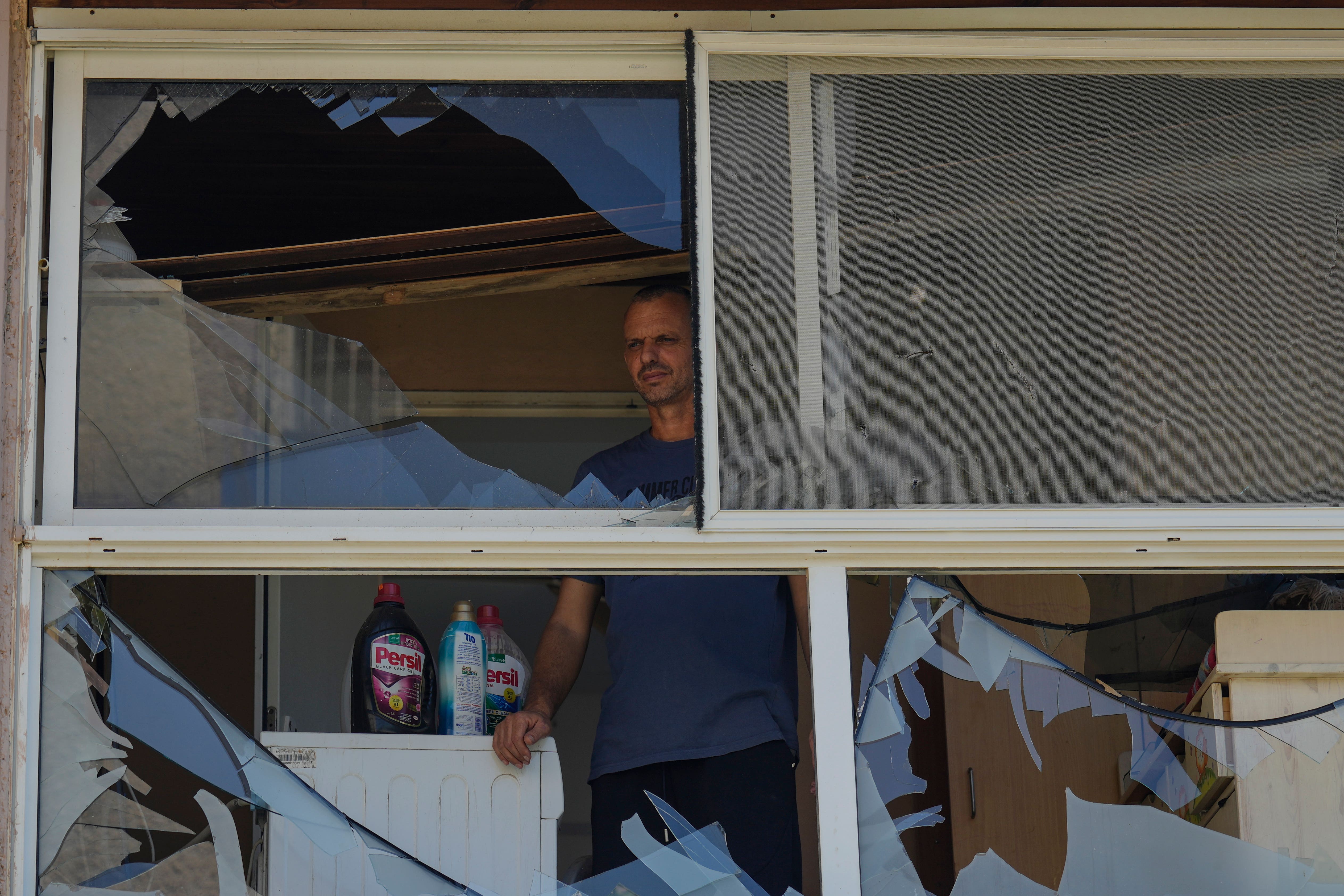 A man looks at a damaged window of a house following an attack in Acre, north Israel