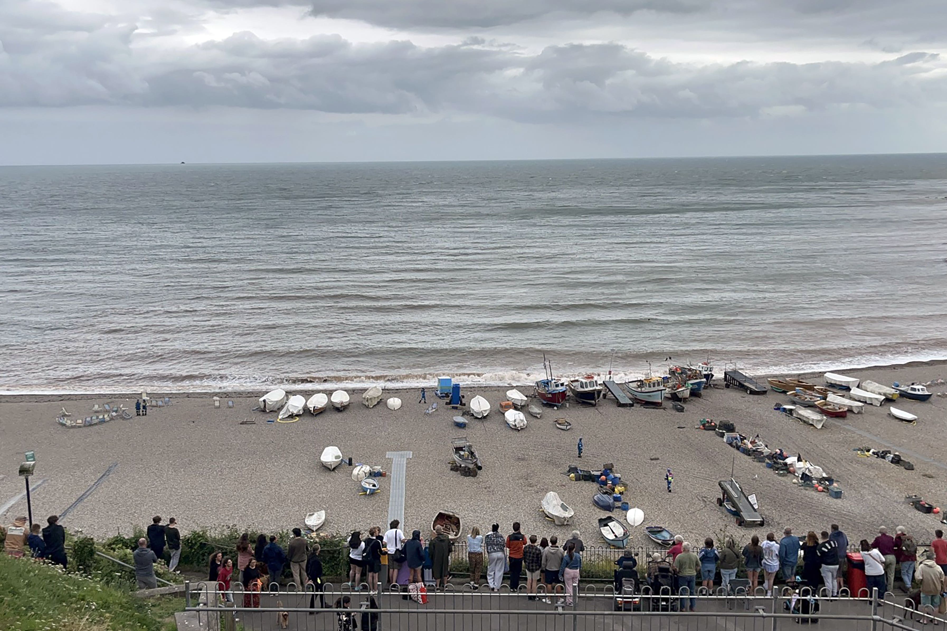 A crowd of people look down on the closed beach in Beer in east Devon after the discovery of a suspected bomb