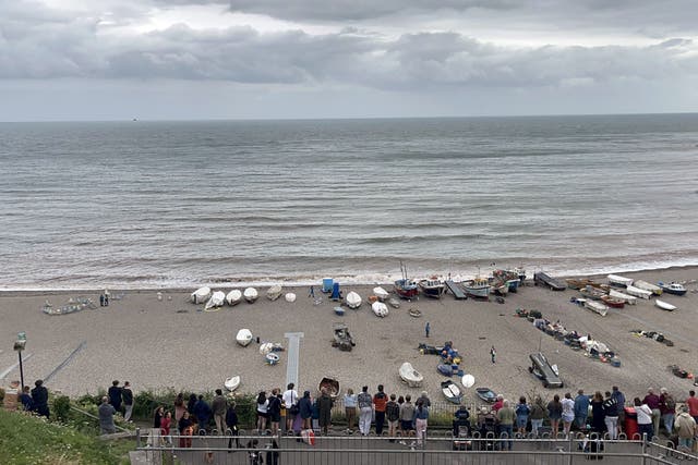 <p>A crowd of people look down on the closed beach in Beer in east Devon after the discovery of a suspected bomb </p>