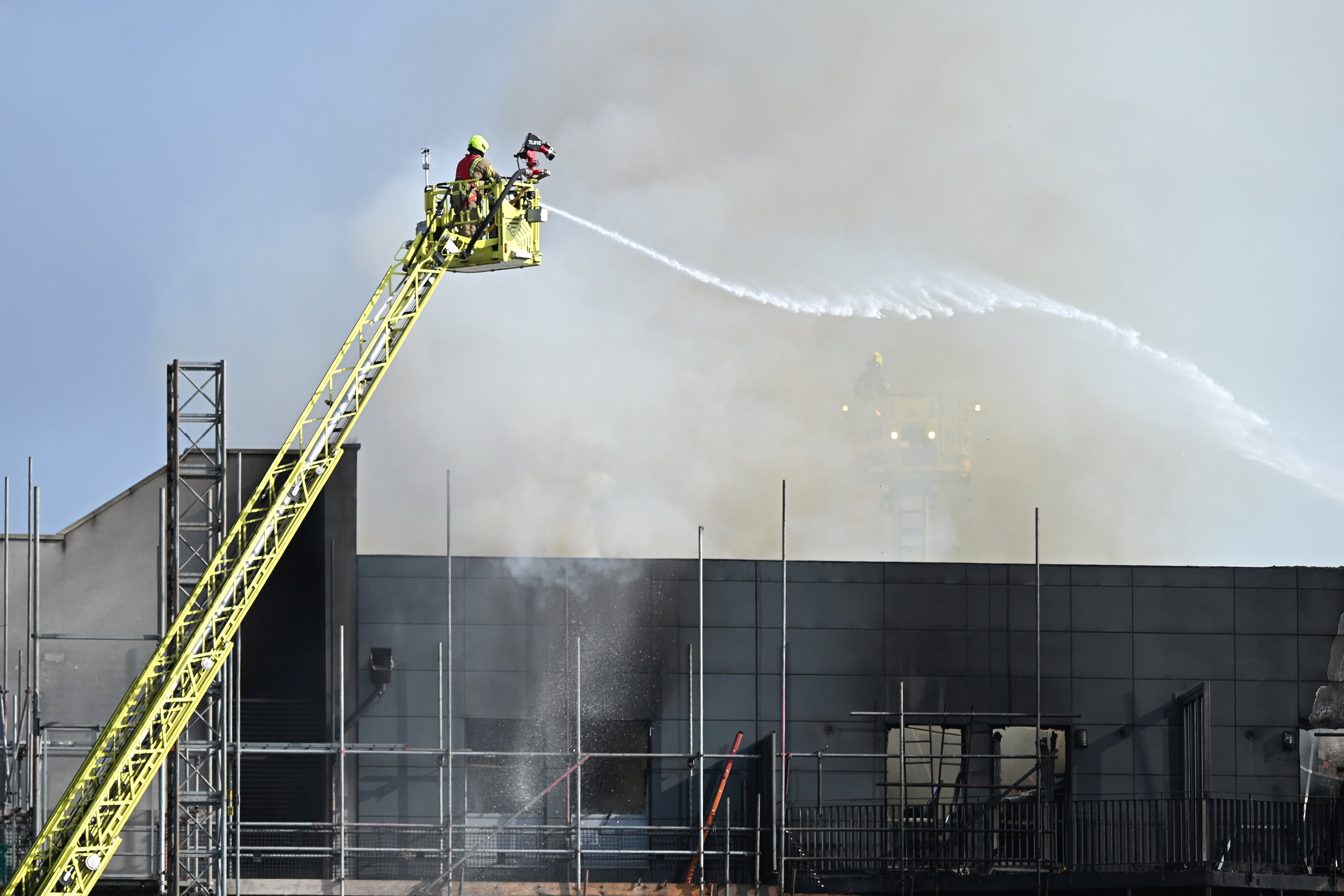 Firefighters spray water over the blackened shell of Spectrum House, Dagenham