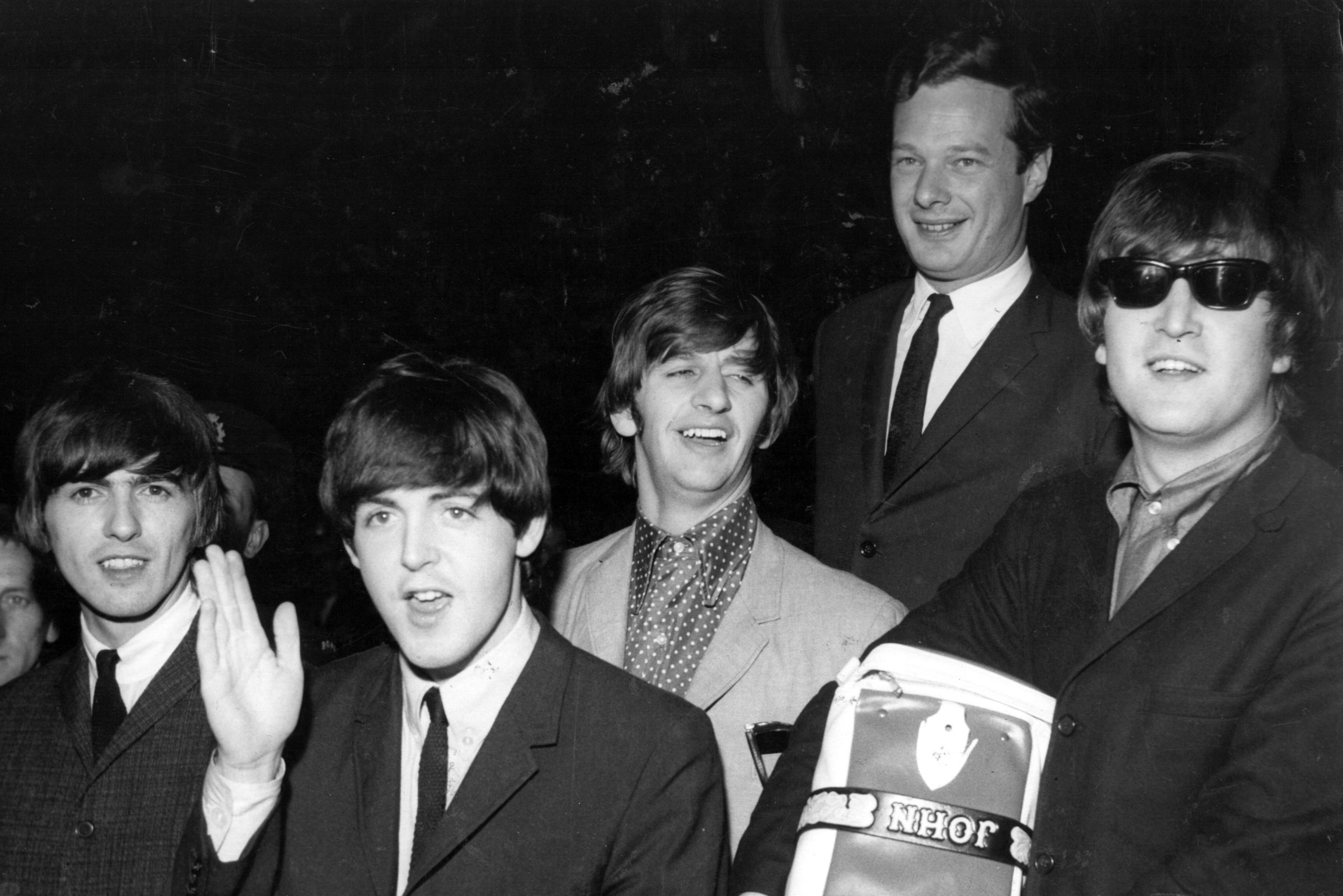 L-R: George Harrison, Paul McCartney, Ringo Starr, Beatles manager Brian Epstein and John Lennon at London Airport after concluding their second tour of the US