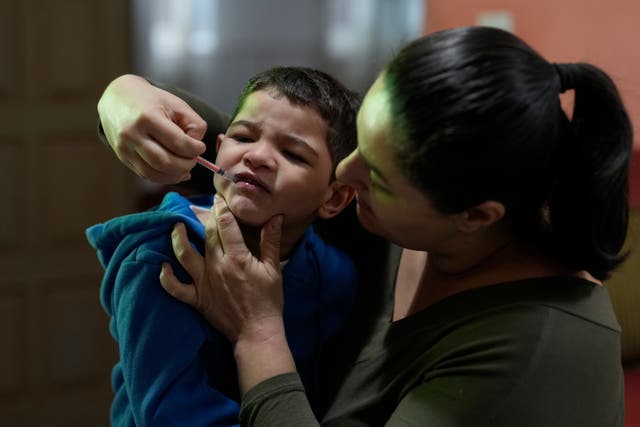 <p>Janaina Silva gives a dose of cannabidiol or CBD, to her four-year-old son Murillo</p>