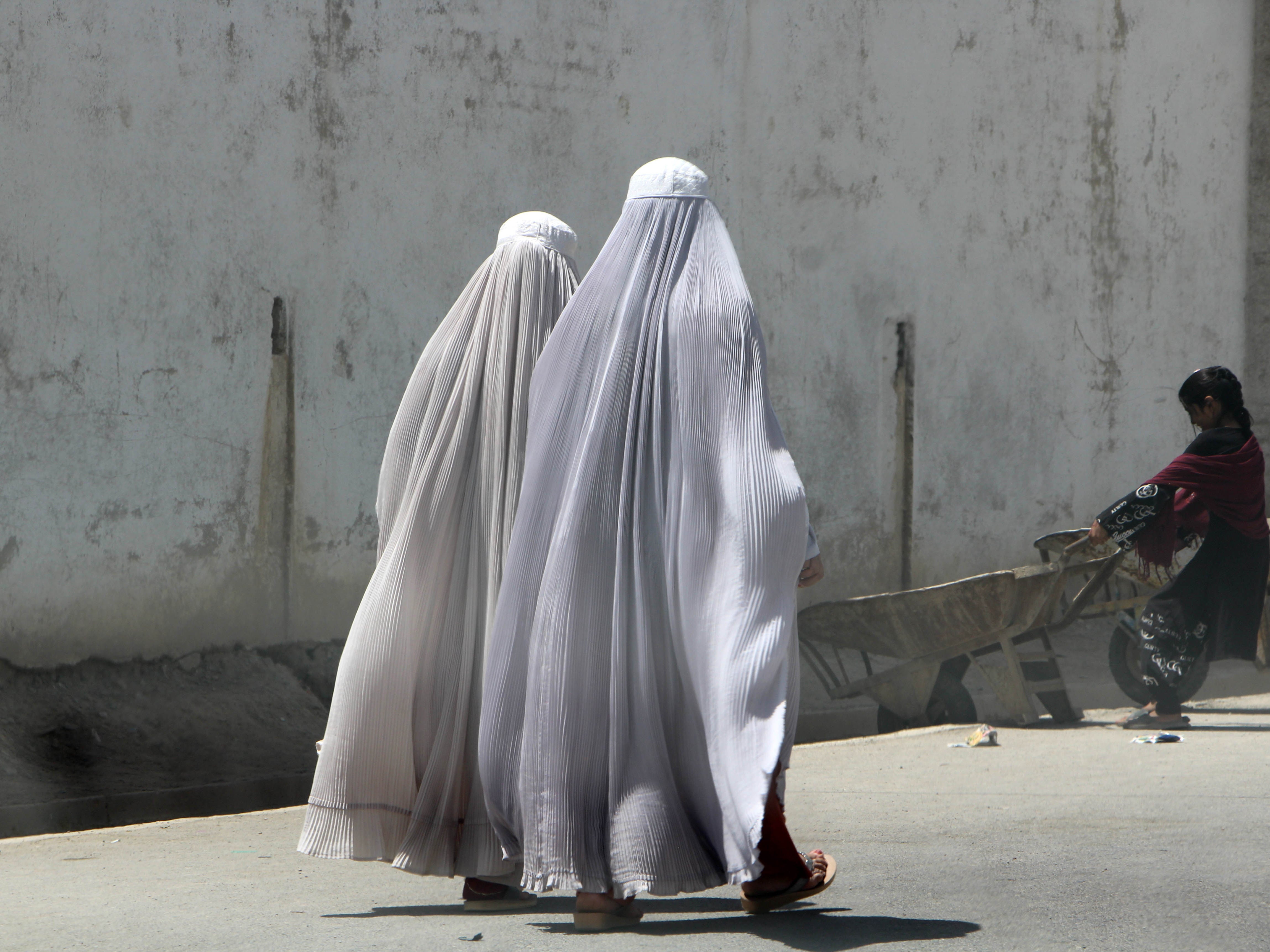 Afghan women walk on a road in Kandahar, Afghanistan. The Taliban has enforced new laws mandating women must hide their bodies, faces and voices in public