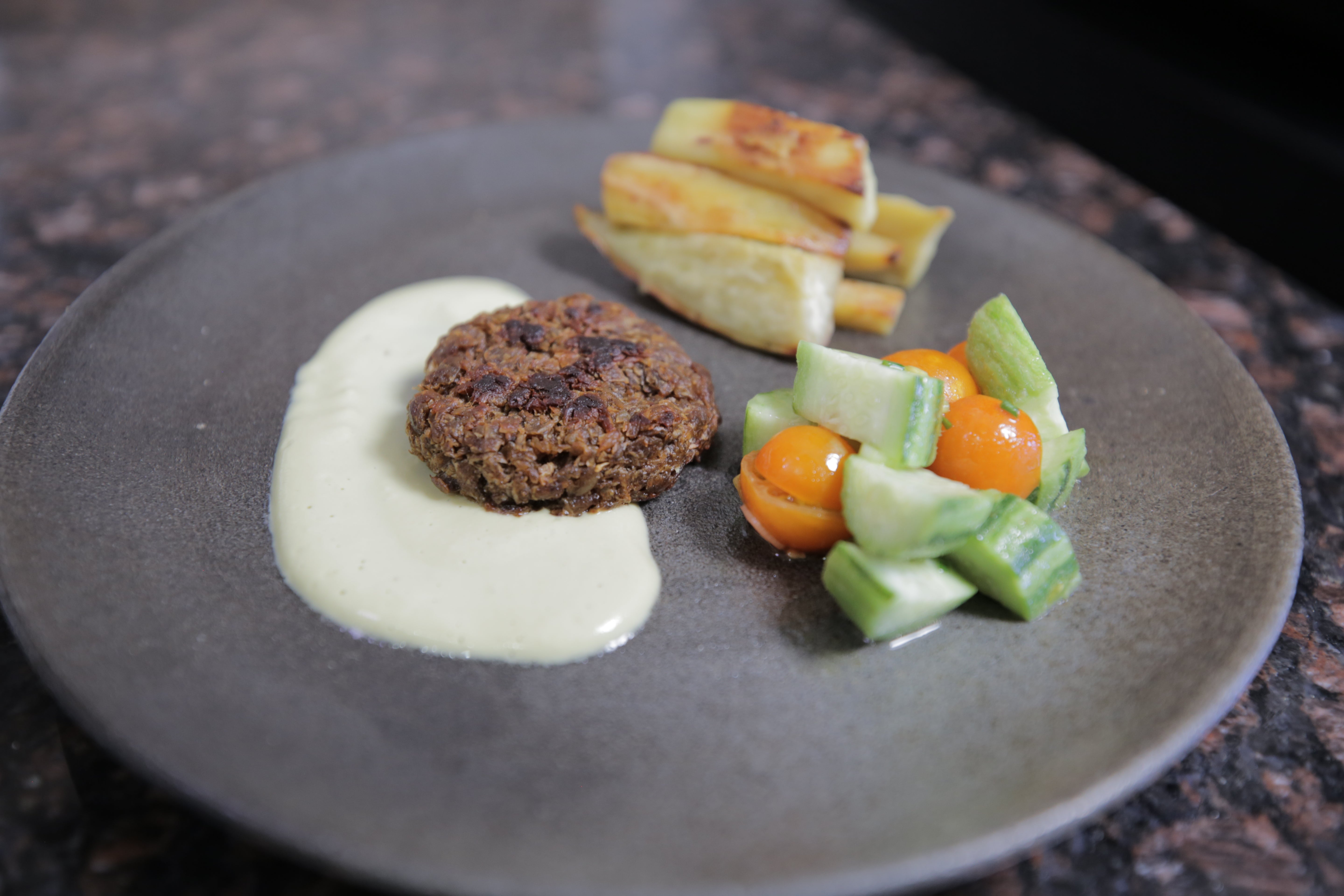 A sautéed patty made from soy mash inoculated with Neurospora mold and fermented for several days. Vayu Hill-Maini, a postdoctoral fellow at UC Berkeley, prepared and cooked the patty and served it with a cashew cream sauce, baked yams, and a fresh cherry tomato and cucumber salad.