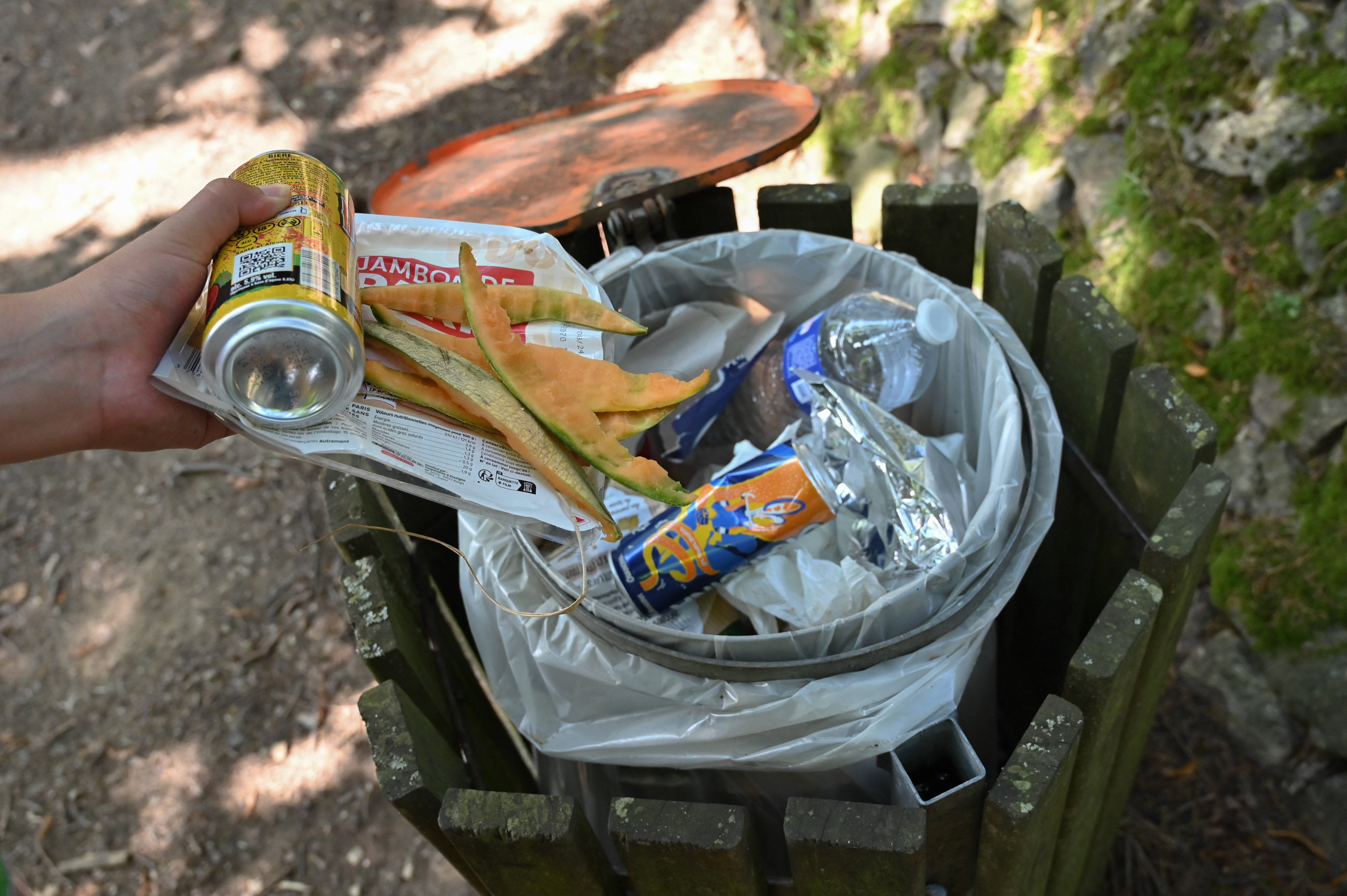 A woman throws leftover food and melon peels into a public trash can after a picnic on the shore of Lake Ternay in Saint Marcel les Annonay, France.