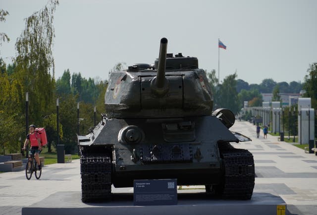 <p> A delivery man rides a bicycle past a WWII t-34 tank in downtown Kursk</p>