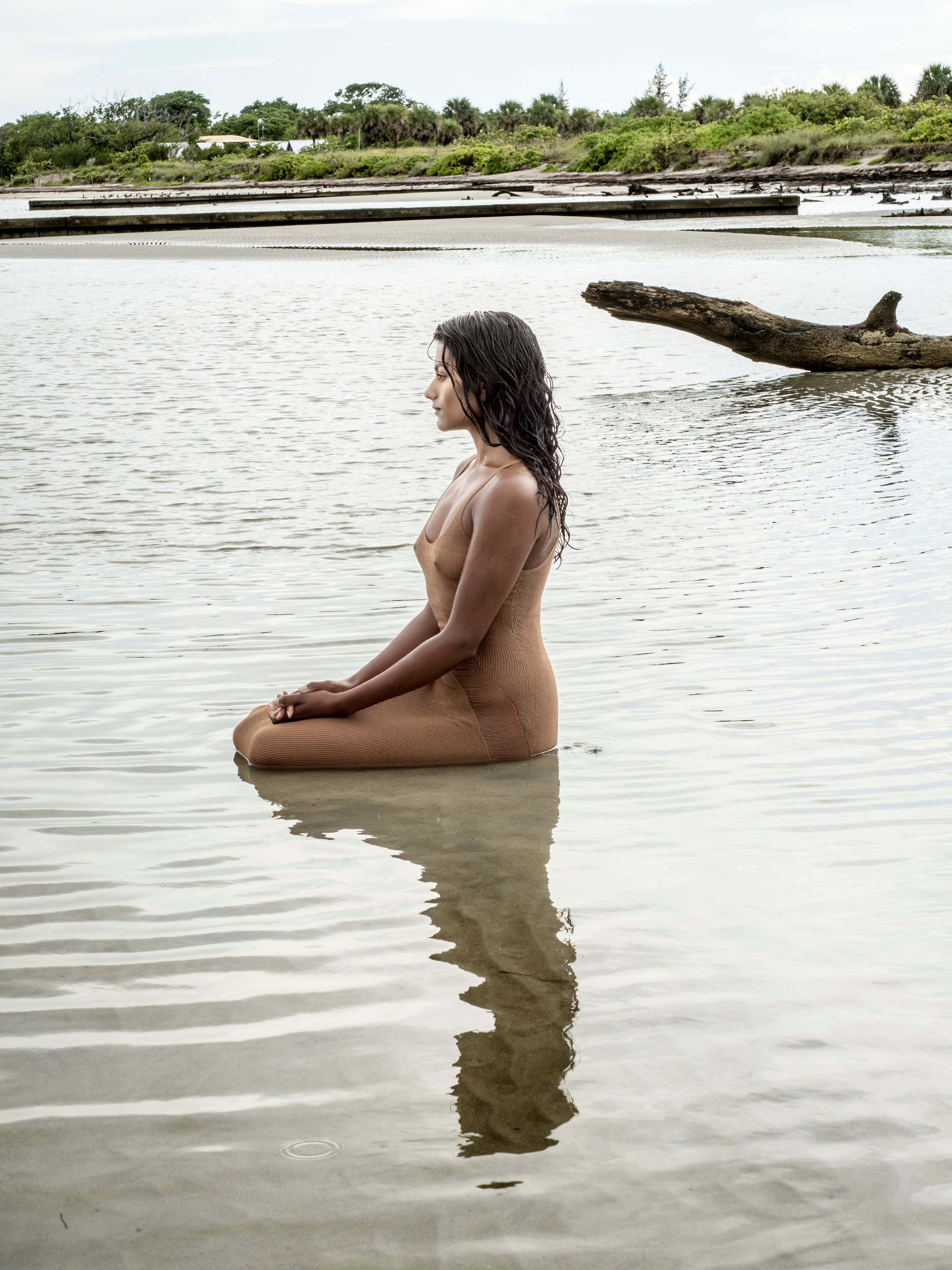 Simone Ashley sits in shallow water on a protected beach in the Miami Keys