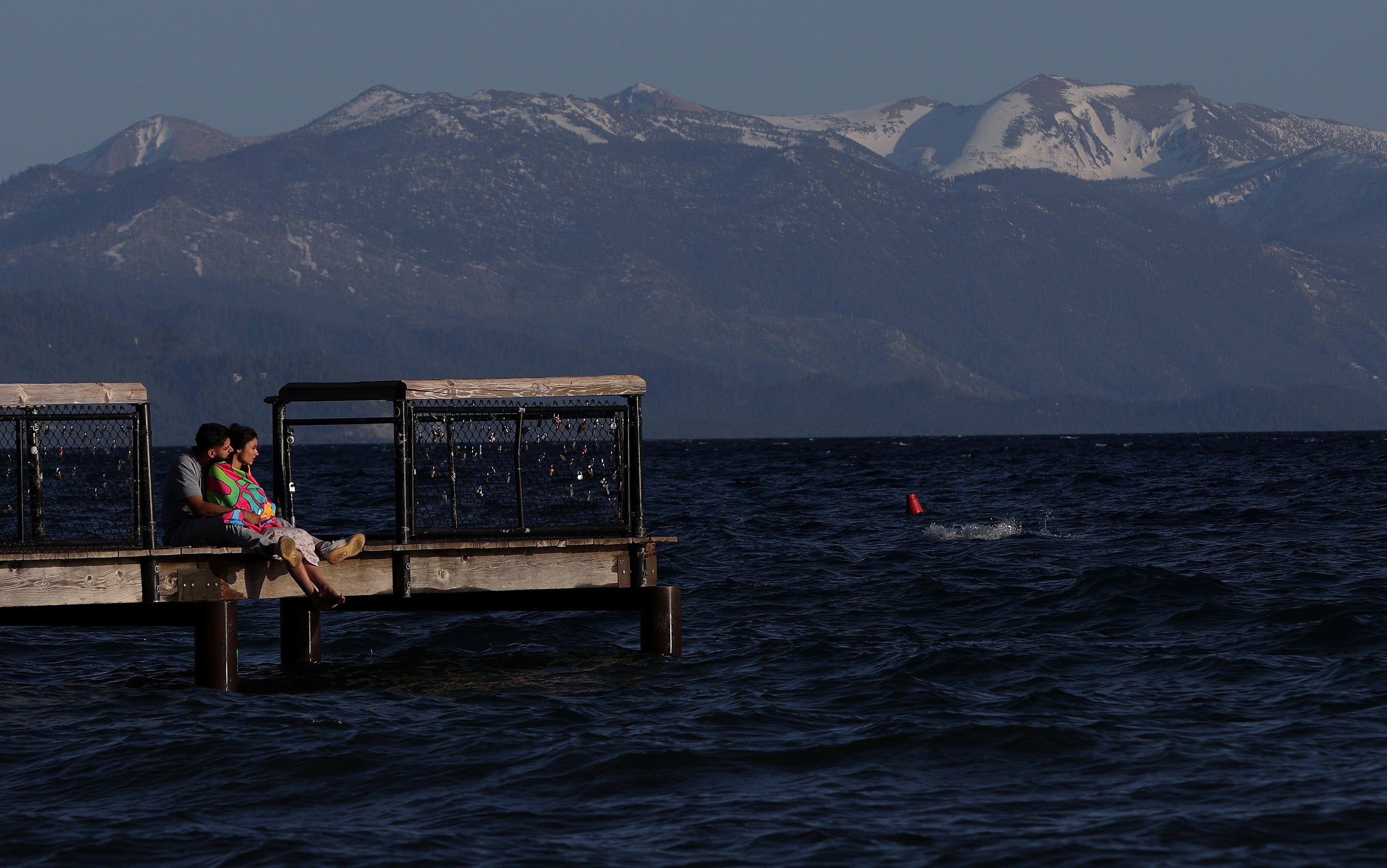 <p>Park visitors sit on a dock over Lake Tahoe at Kings Beach</p>
