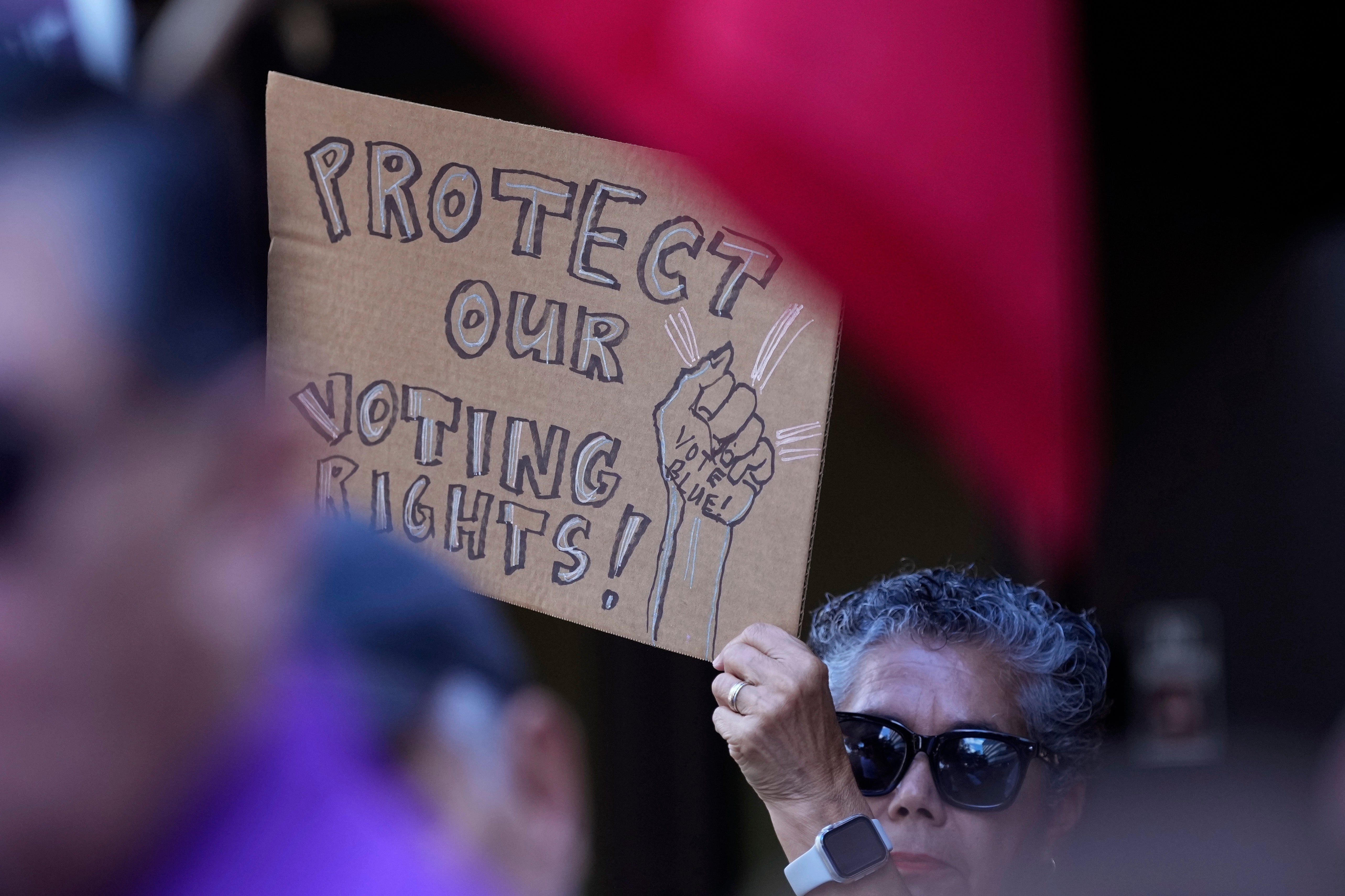 A supporter waves a sign at a news conference where officials with LULAC held a news conference to respond to allegations by Texas Attorney General Ken Paxton on Monday