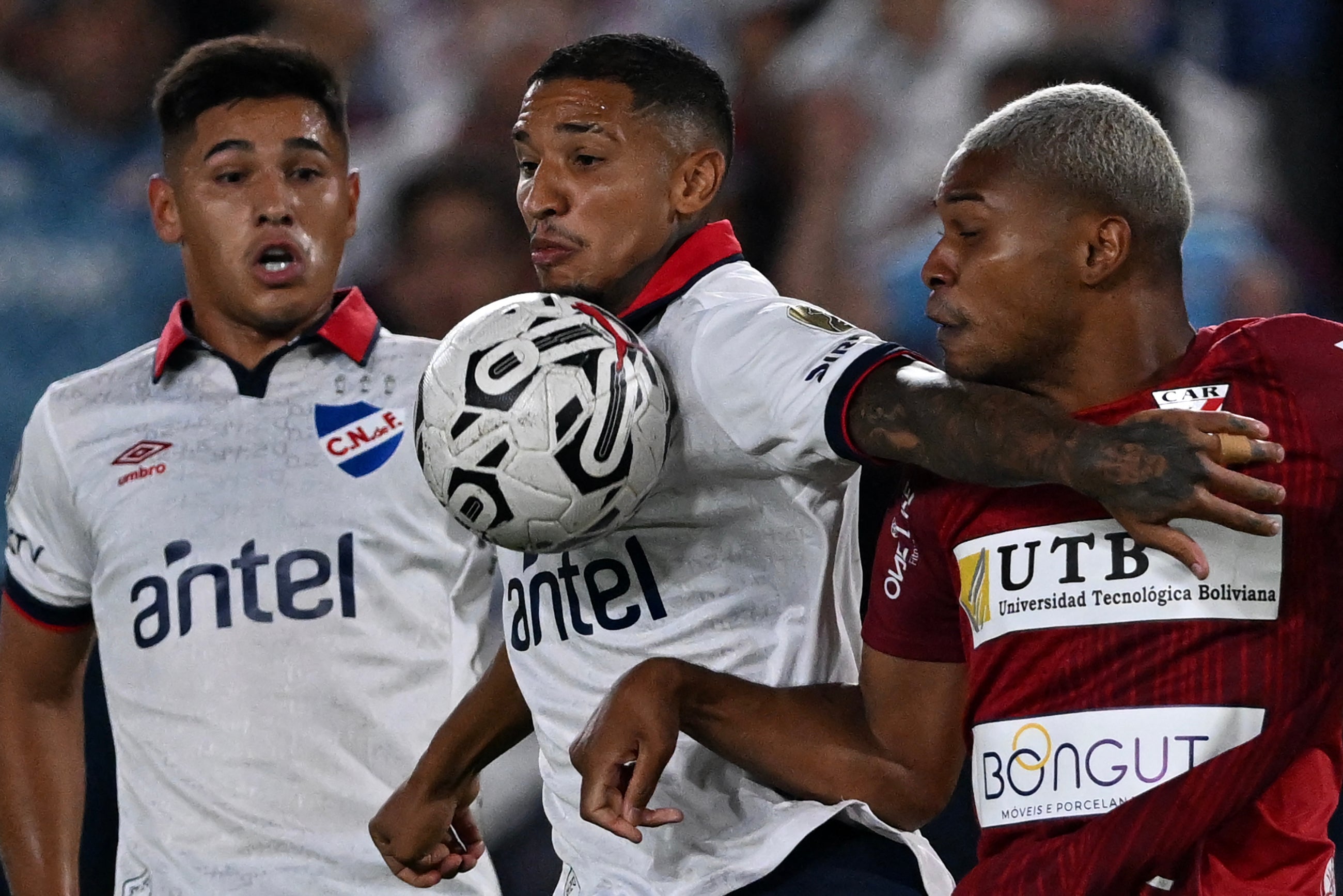 Nacional's defender Juan Manuel Izquierdo (C) and Always Ready's Brazilian forward Wesley Tanque fight for the ball