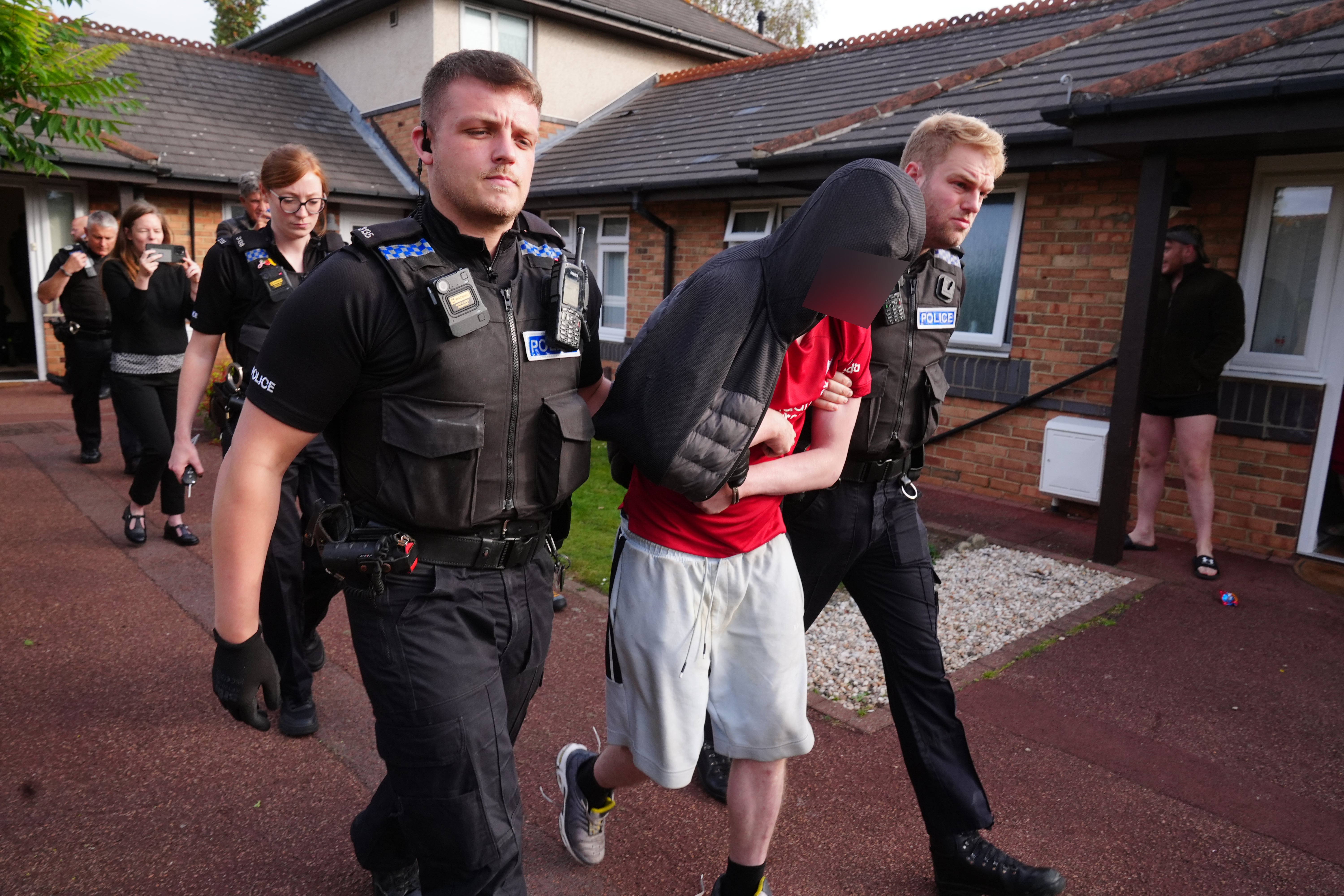 Cleveland Police officers escort a man they've arrested in Middlesbrough during a day of action following the recent disorder.