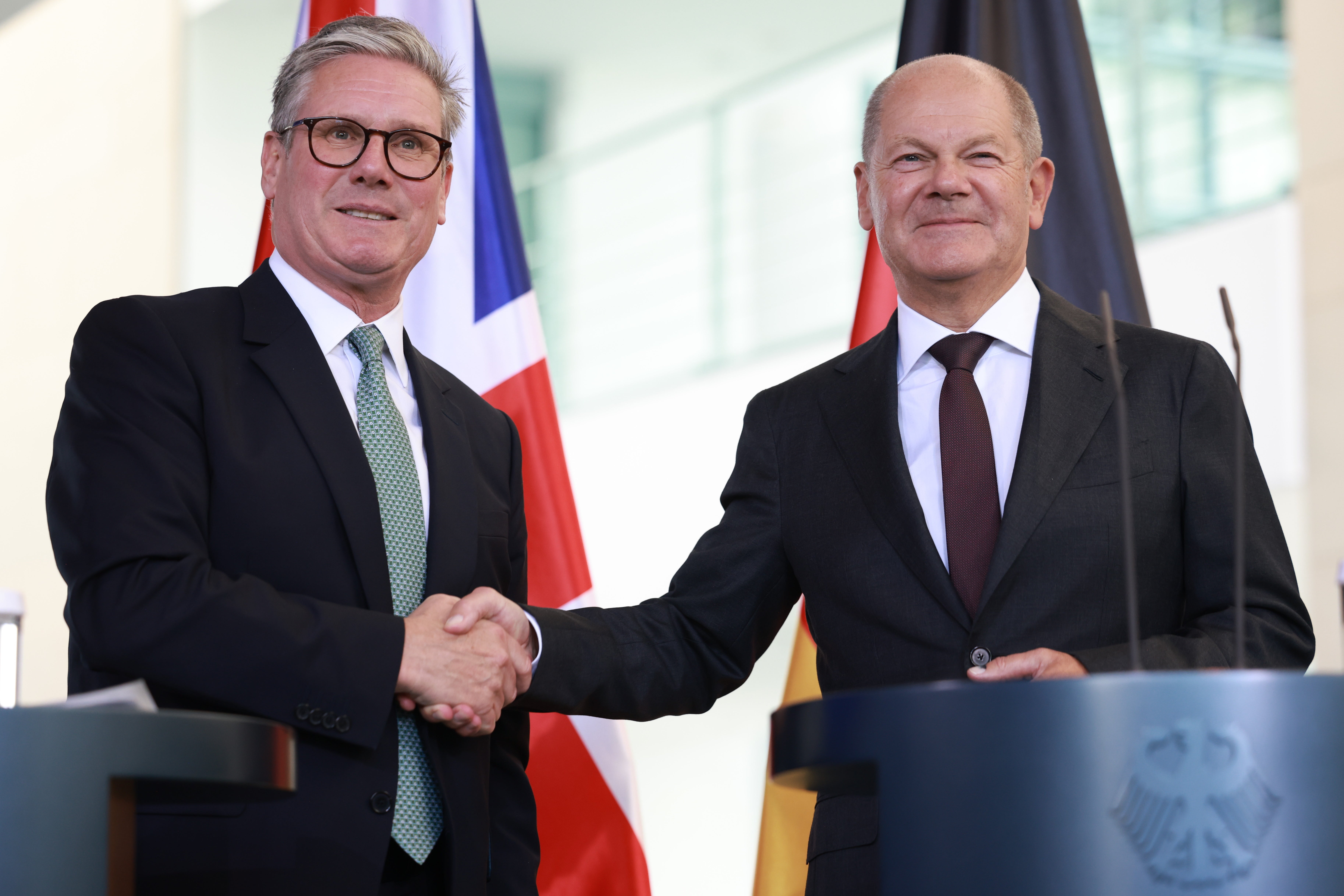 German Chancellor Olaf Scholz (R) shakes hands with British Prime Minister Keir Starmer (L) during a joint press conference at the chancellery in Berlin, Germany