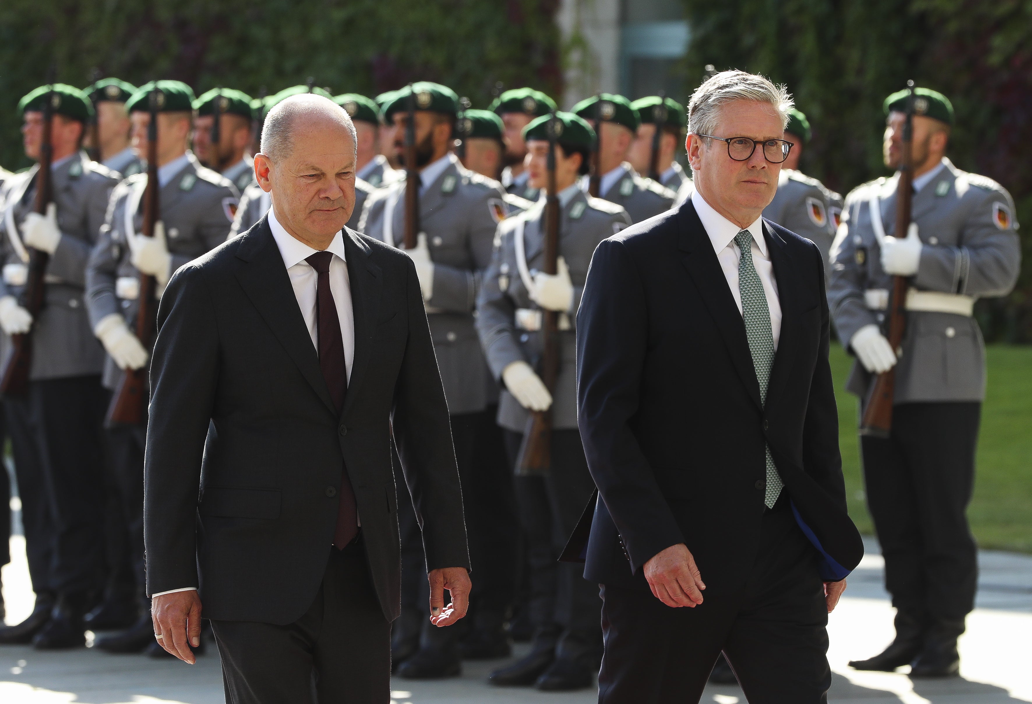 German Chancellor Olaf Scholz (L) and British Prime Minister Keir Starmer (R) review a military honor guard during an official welcome ceremony at the Chancellery in Berlin, Germany