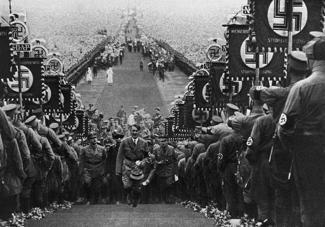 <p>Adolf Hitler ascending the steps at Buckeberg flanked by banner-carrying storm troopers </p>