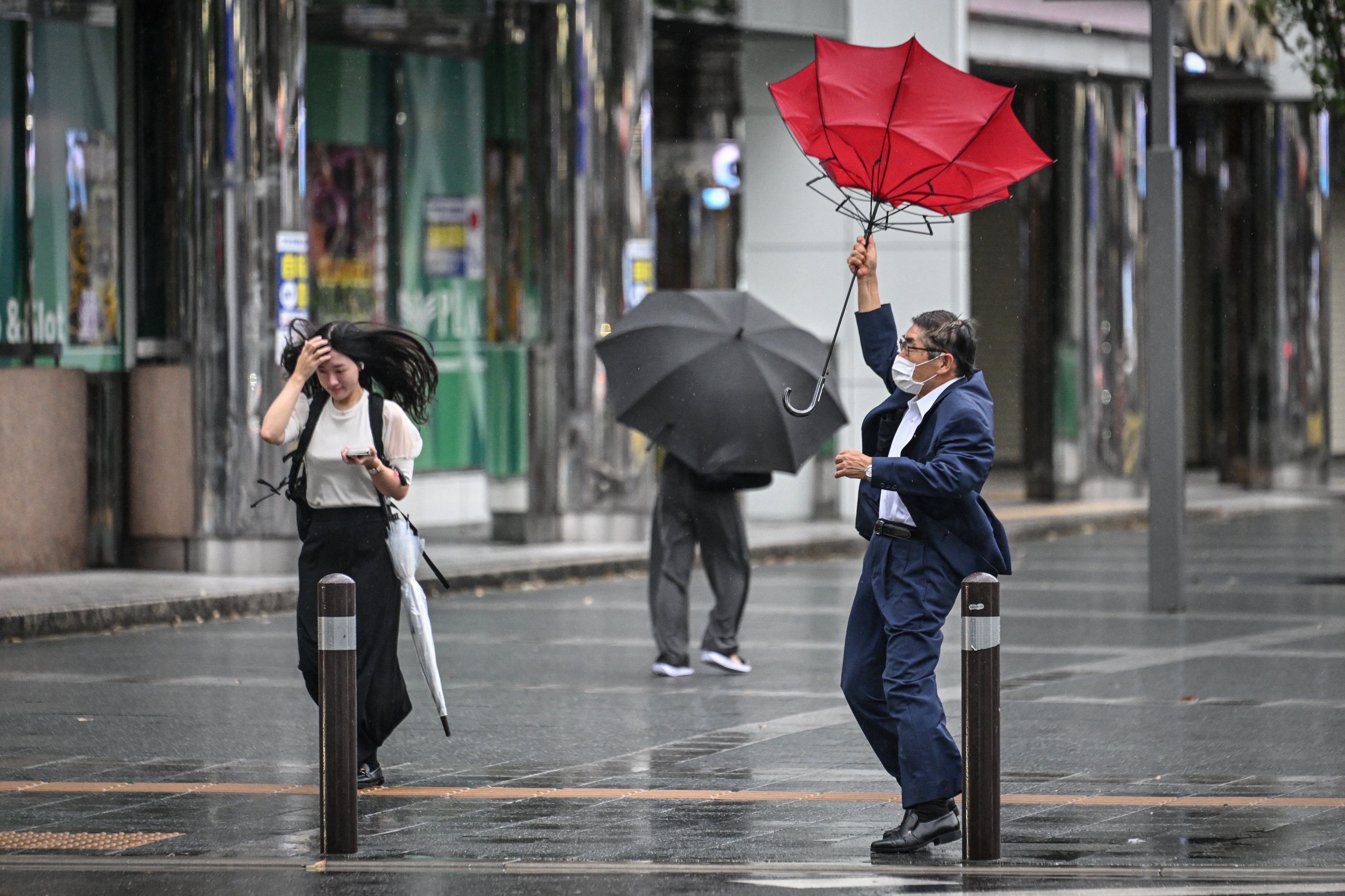 A man holds his umbrella in the wind outside Hakata station in Fukuoka, Japan