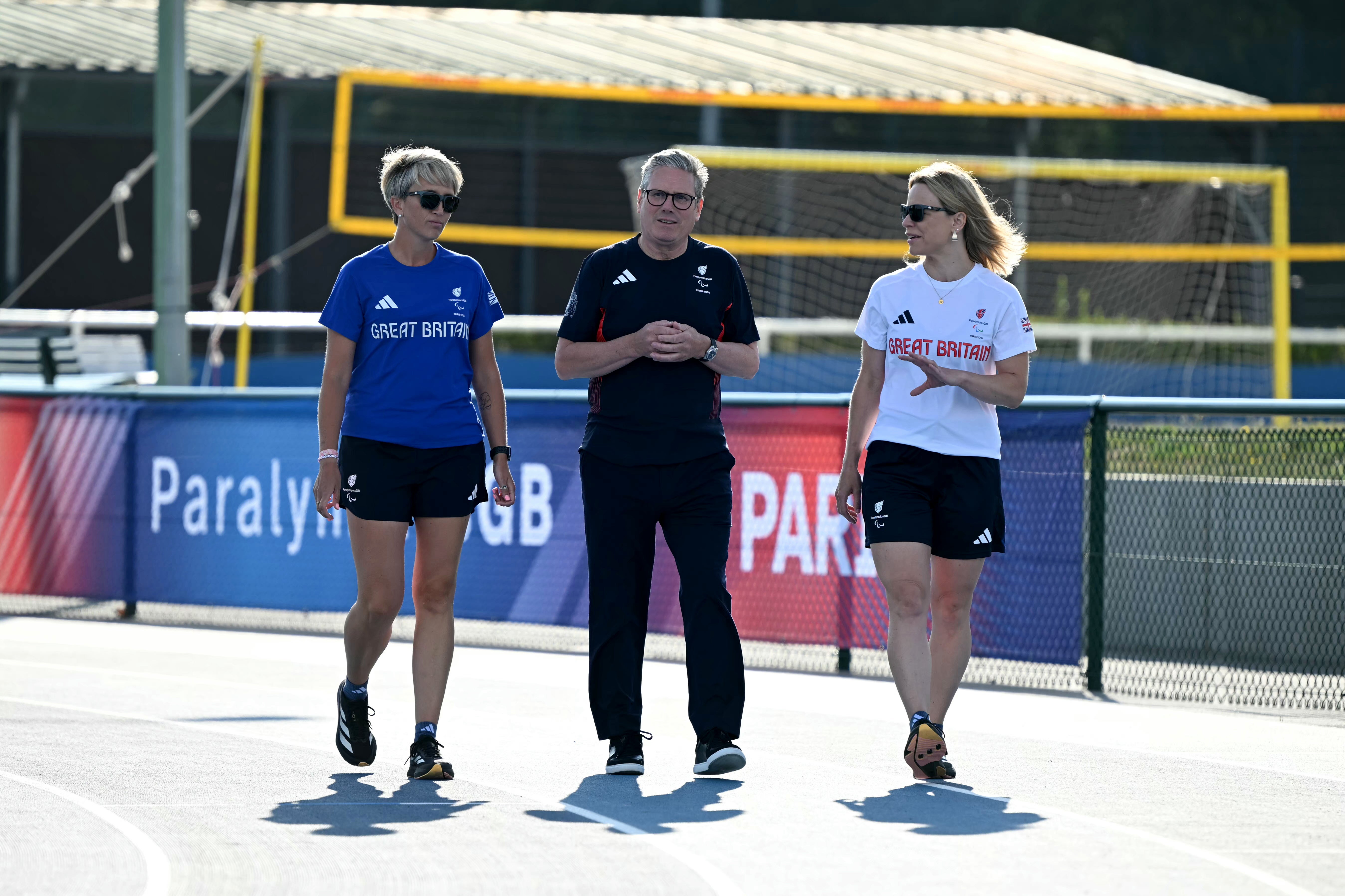 Keir Starmer (C) walks on a track with team manager for athletics for British athletes Pamela Robson (L) and head of preparations Maria Adey (R) at a training centre in Saint-Germain-en-Laye, north-west of Paris, on August 29, 2024 in Paris, France. Starmer arrived in Paris