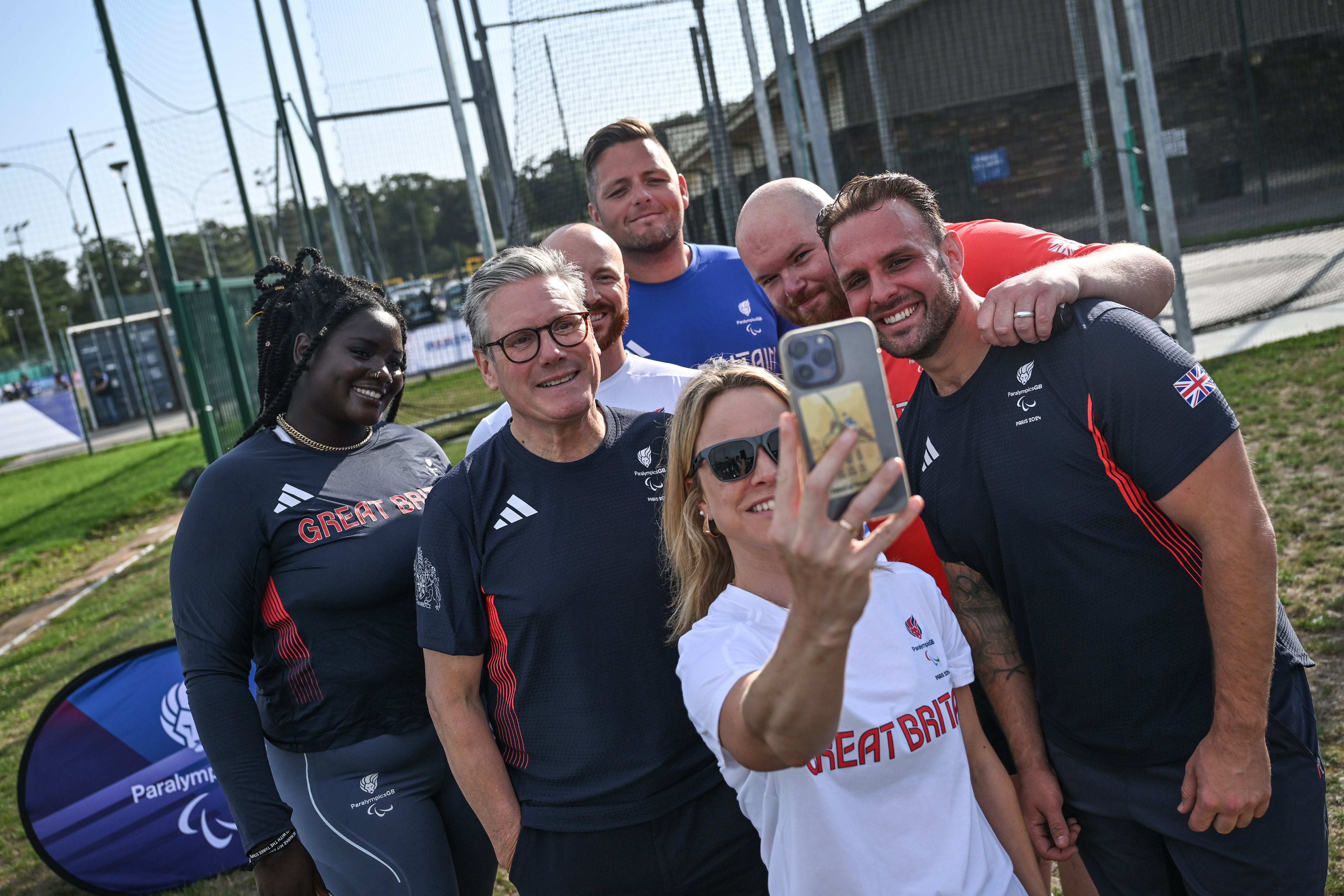 Keir Starmer (2-L) poses for selfies with British athletes Daniel Pembroke (3-L), Aled Davies (R), Funmi Oduwaiye (L) and head of preparations Maria Adey