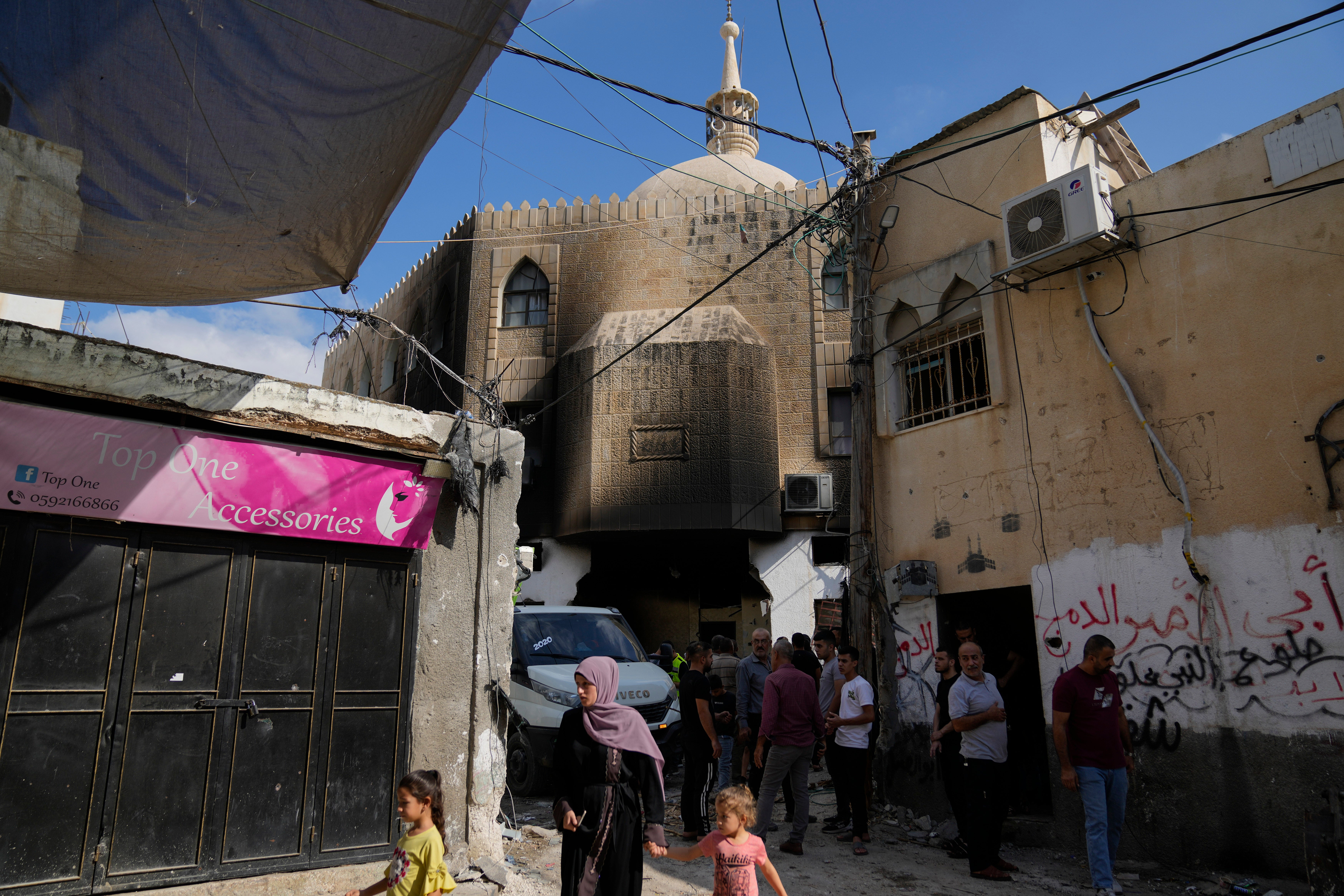 Palestinians stand outside the damaged mosque in the West Bank