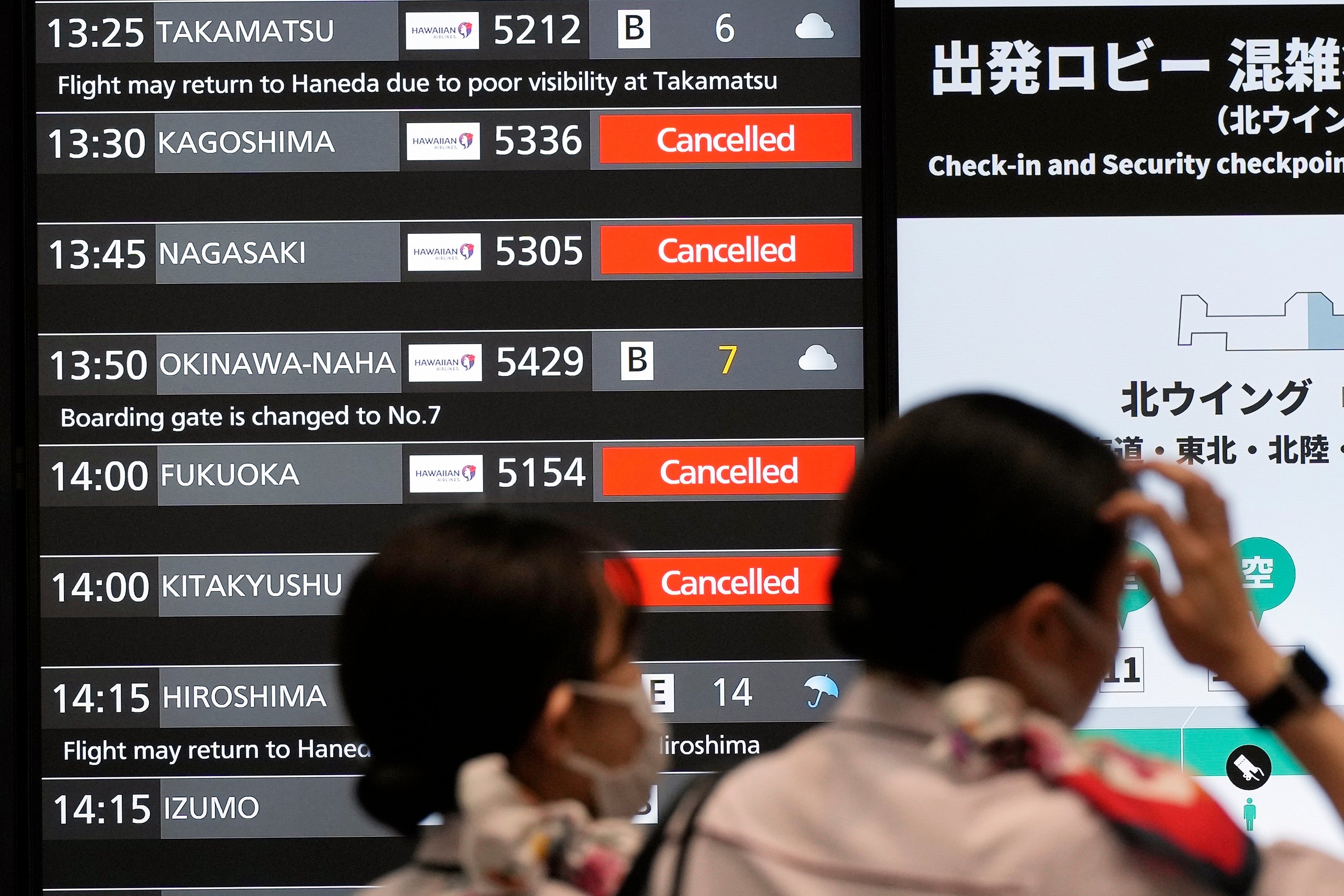 A departing flight information board shows that some flights were cancelled due to an approaching Typhoon Shanshan at Haneda airport