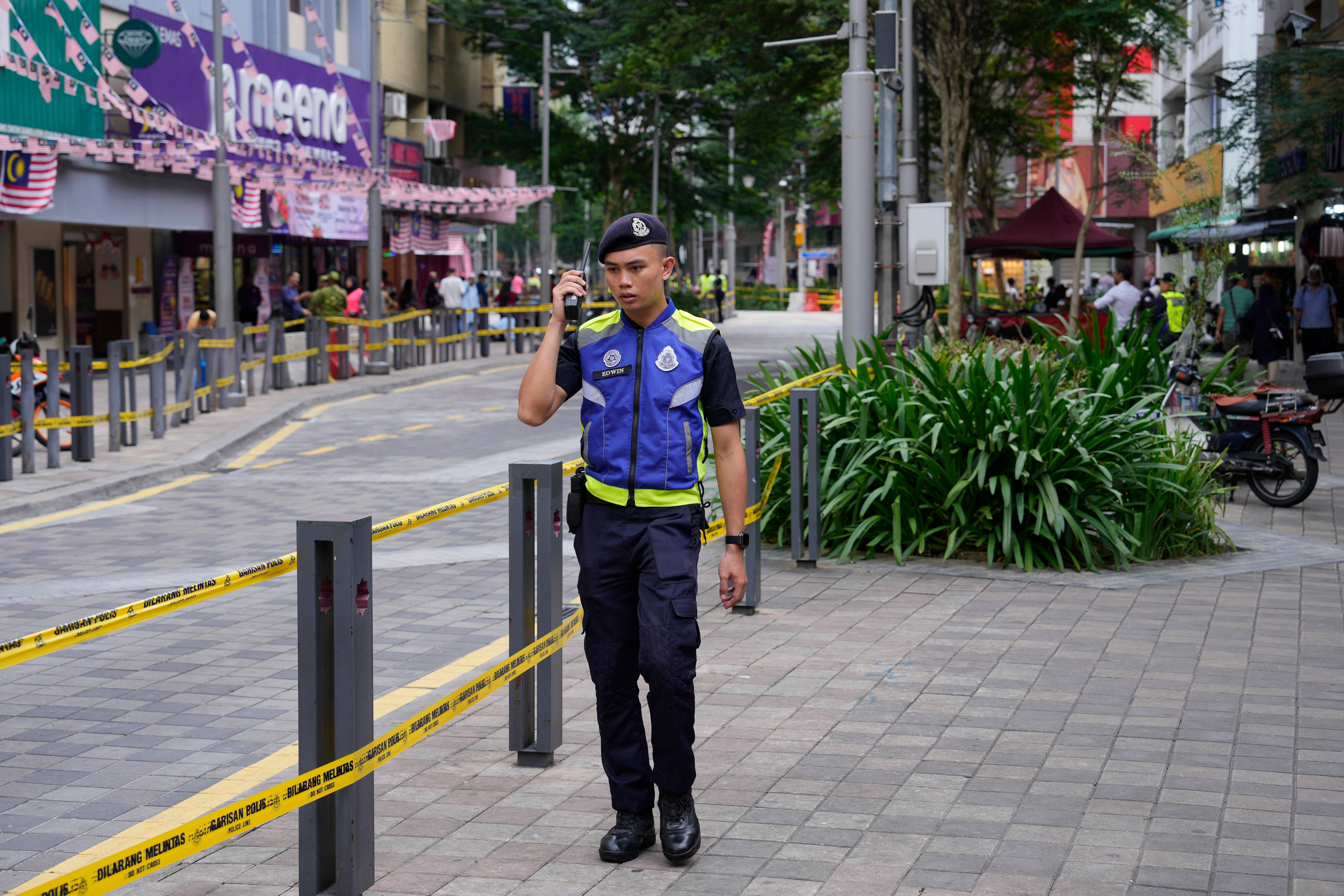 Police stand guard on a closed roadside after another deep sinkhole appeared a week after a woman fell into a sinkhol