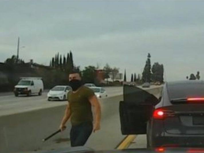 Nathaniel Radimak approaches a truck with a pipe in his hand after exiting his Tesla