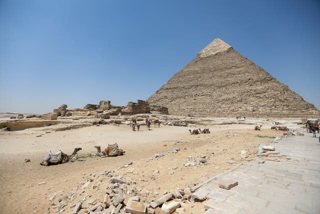 <p>Tourists walk past pyramids of Khufu, Khafre, and Menkaure in Giza</p>